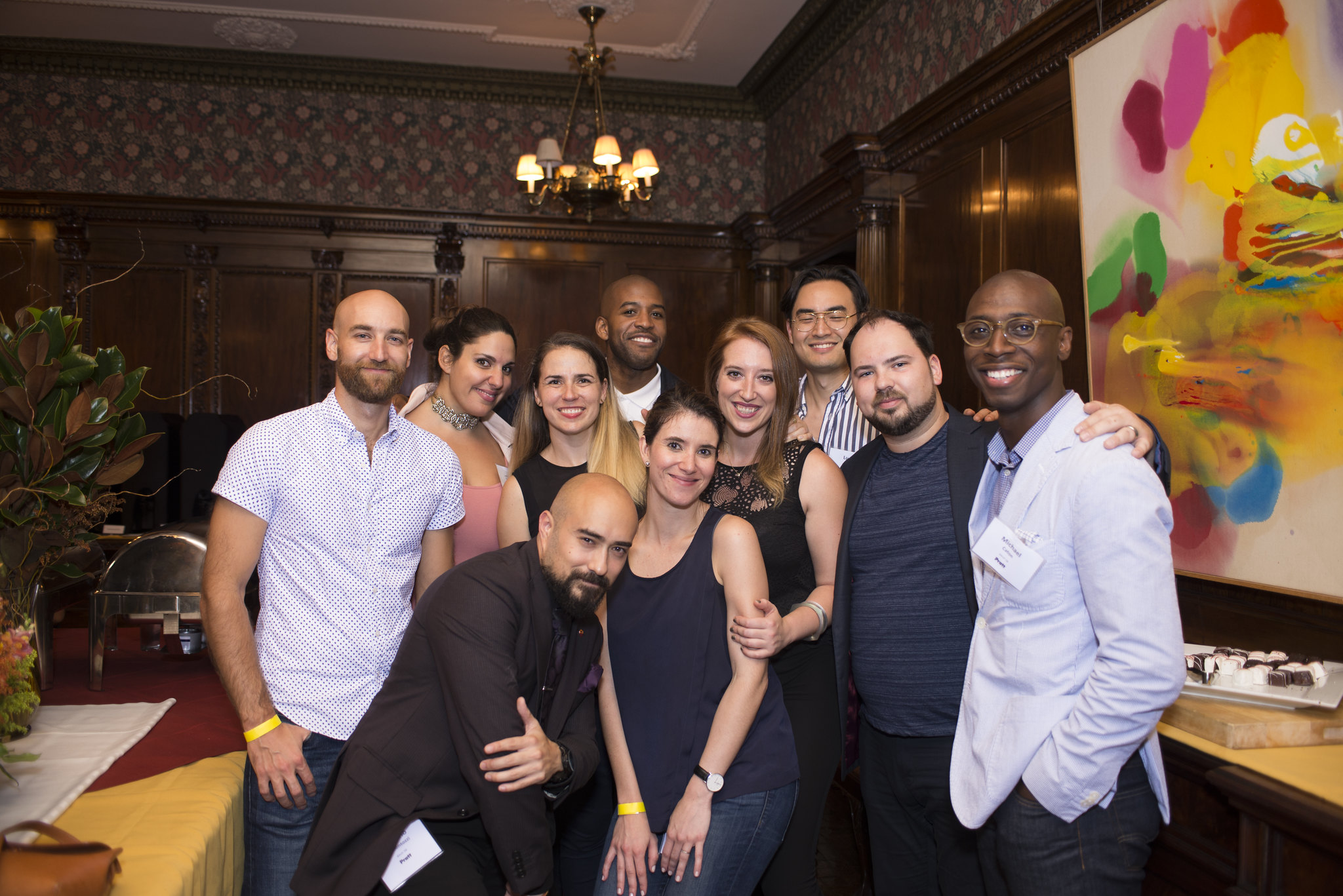 a group of young alumni, standing and posing, while smiling