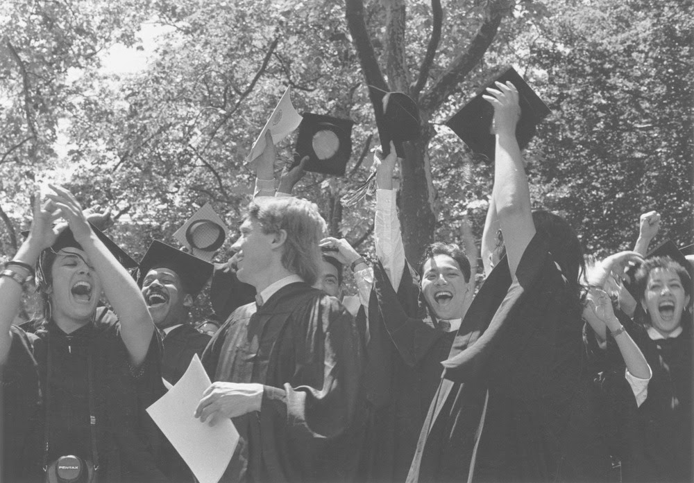 Group of students in park, throwing hats, smiling