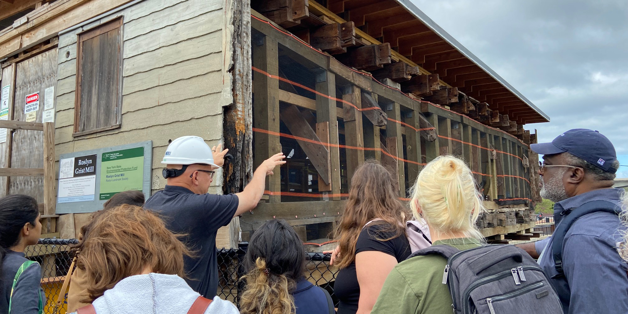 A group of students listen to a worker at the Roslyn Grist Mill restoration site talking about the project.