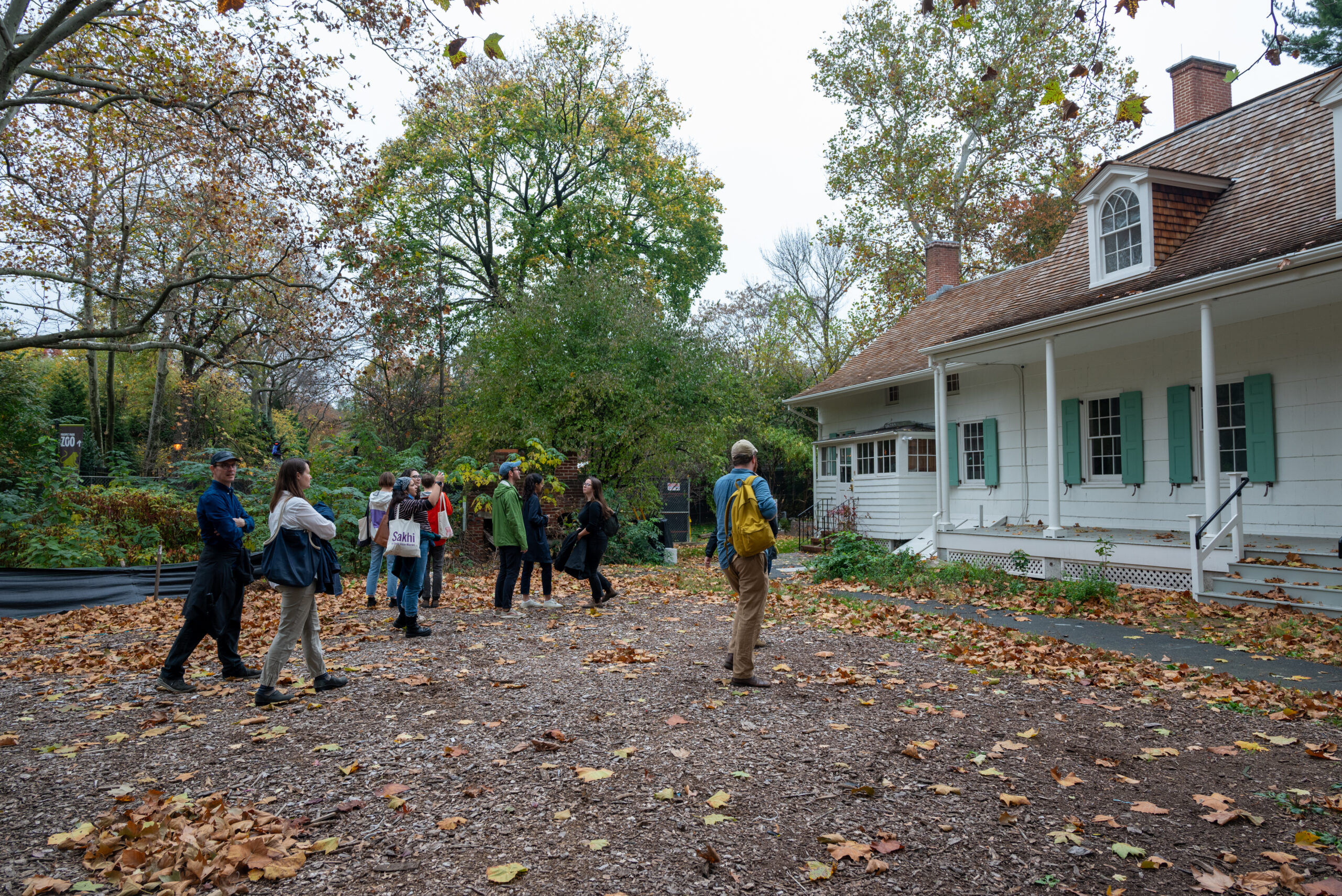 Group of students approaches white colonial house in tree-filled lot