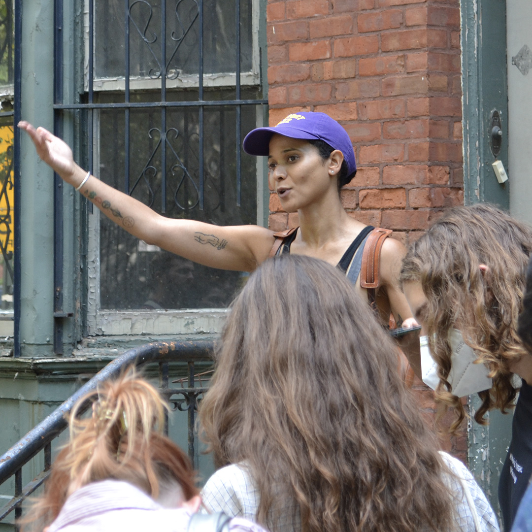 Member of the Pratt community, speaking to a group of students on a stoop