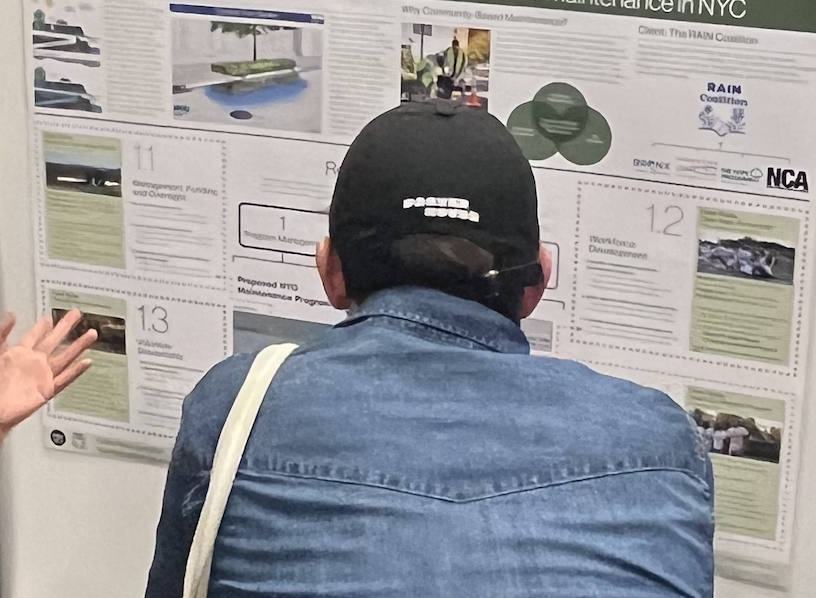 student hunched in front of a board with information on research, student wearing hat and denim shirt