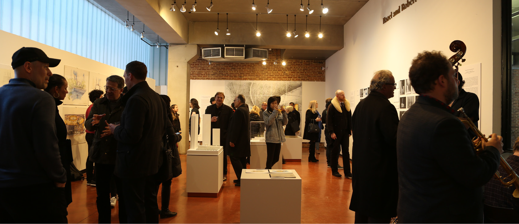 people gathered in an art gallery, looking at pieces displayed