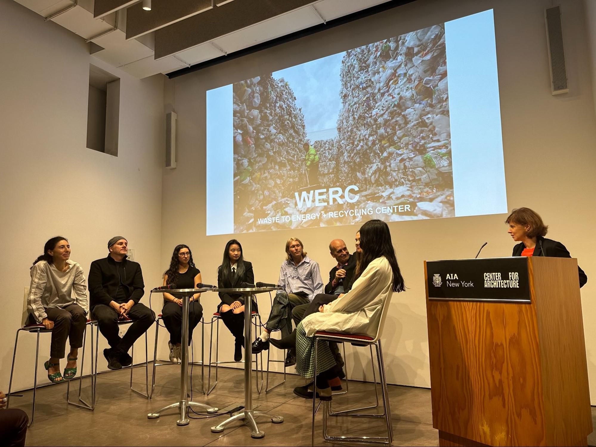 People speaking on a panel, projection of event on wall