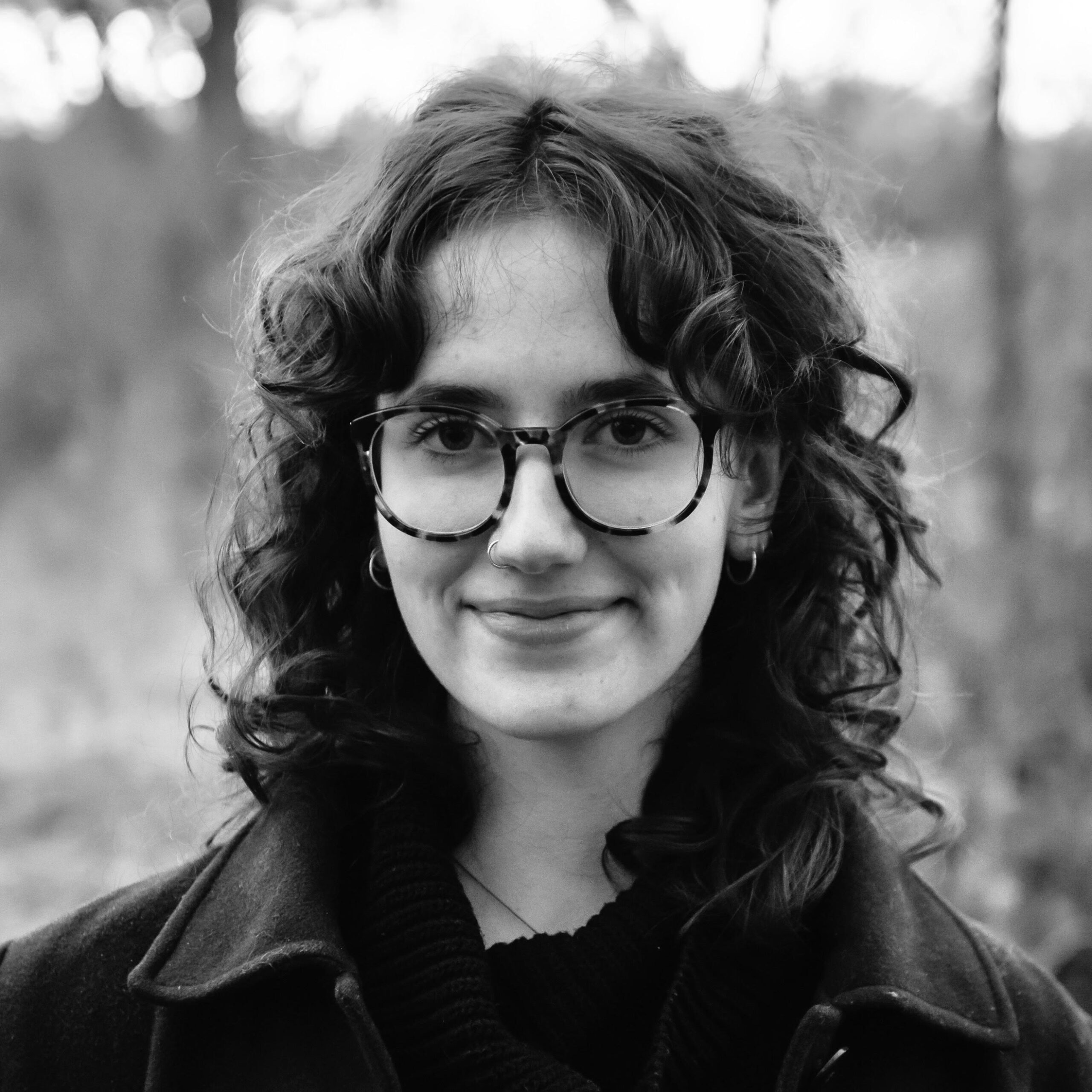 Black and white portrait of a woman with curly hair and glasses.