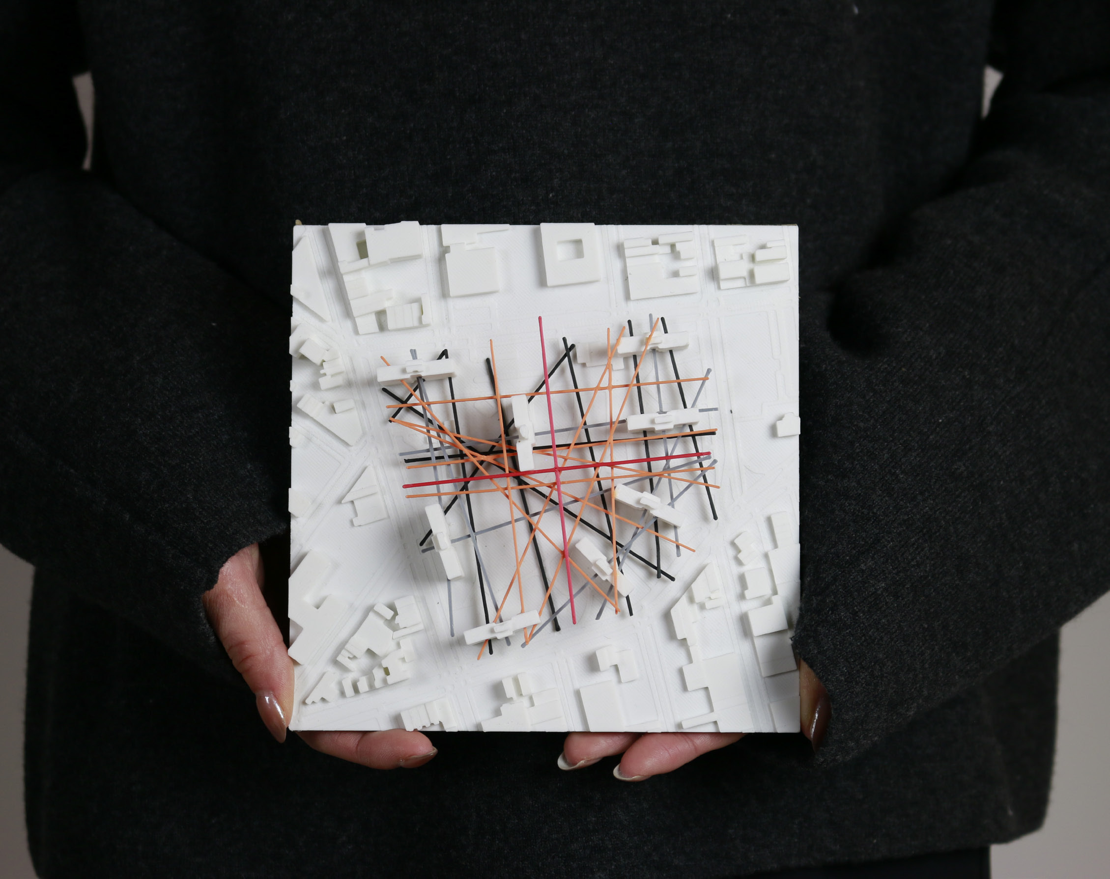 A student holding a process model that analyzes apartment neighborhood's accumulated path, culture, directions and pattern.