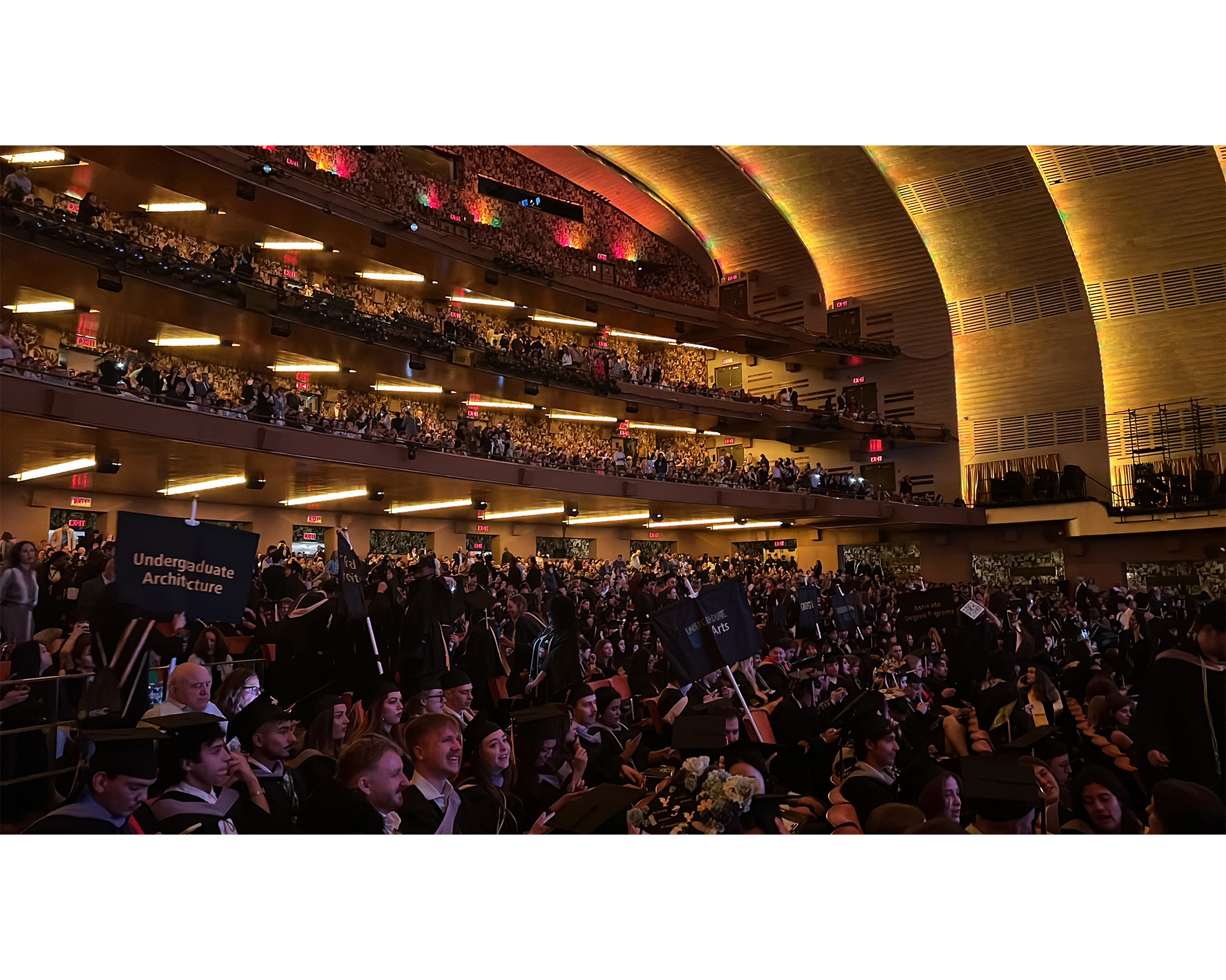 A large group of people seated in a spacious auditorium, engaged in the Spring 2025 Pratt commencement ceremonies.