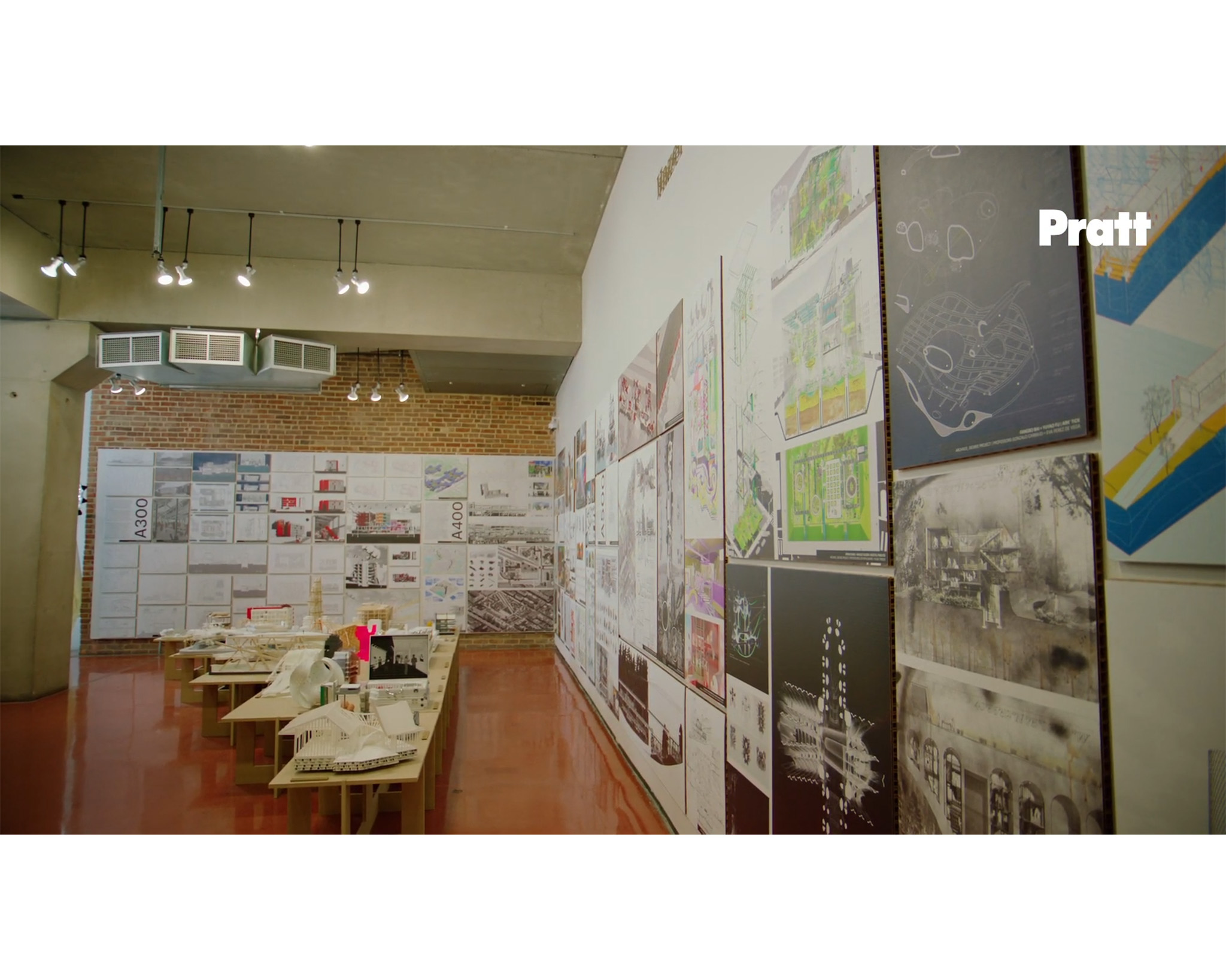 Interior view of architecture exhibition with architectural models in the background.