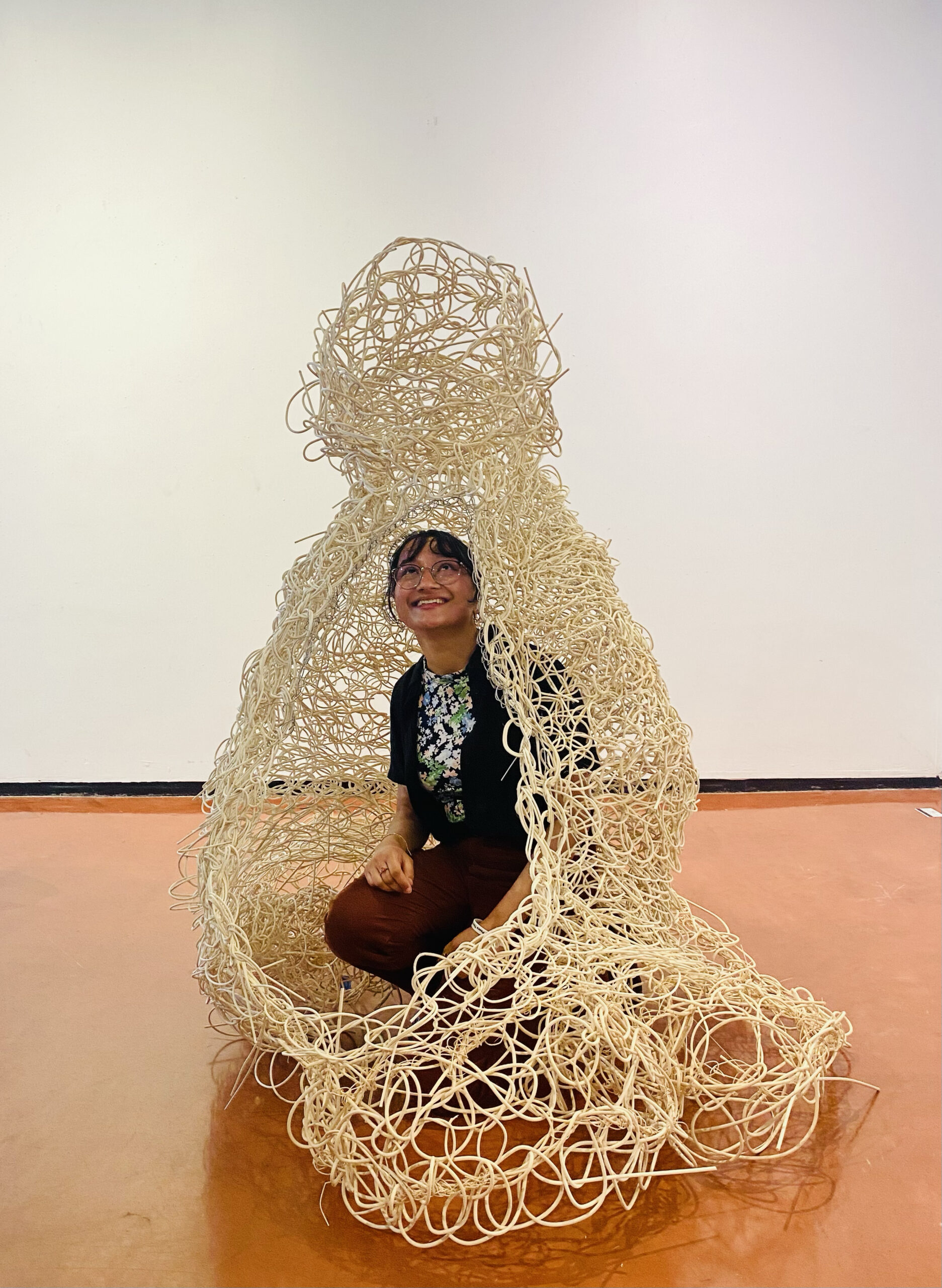SoA Student Rida Khan Tests Hyperstitch Habitat. Student sitting in a crocheted architectural sculpture.