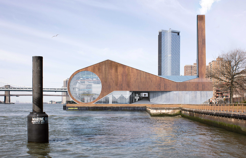 A contemporary waterfront building with a distinctive angular roofline and rust-colored facade, featuring a large circular window on the side facing the water. The structure sits along a boardwalk with a tall smokestack rising from the roof. Behind it, modern high-rise buildings and a bridge are visible, connecting the urban skyline with the riverfront setting.
