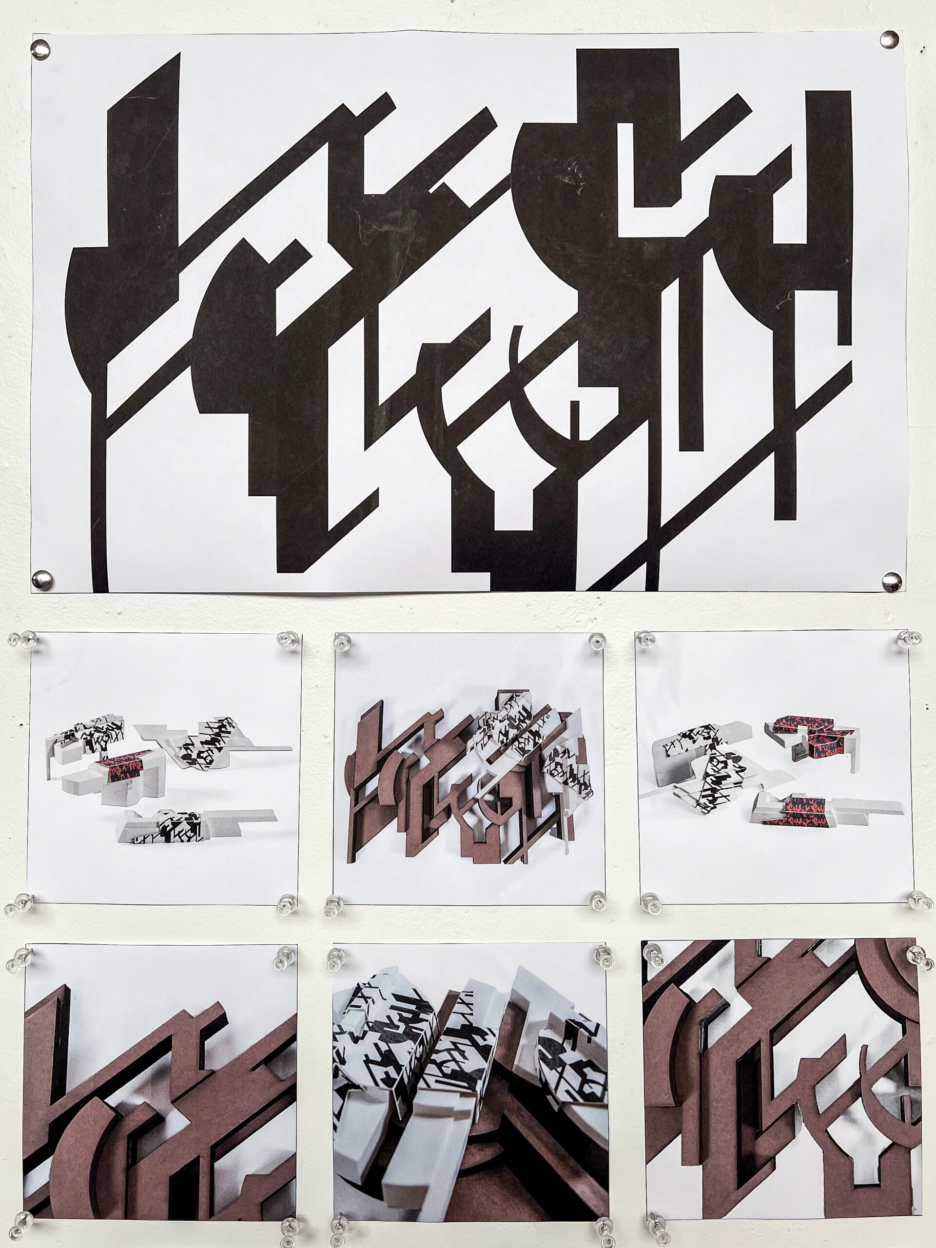 The image shows a series of artistic displays mounted on a wall. At the top, there’s a large black and white graphic featuring abstract geometric shapes and lines. Below, six smaller photographs showcase three-dimensional objects that resemble the shapes in the upper graphic. The objects are arranged in various compositions with contrasting materials, including white and brown surfaces, some adorned with black and red markings.