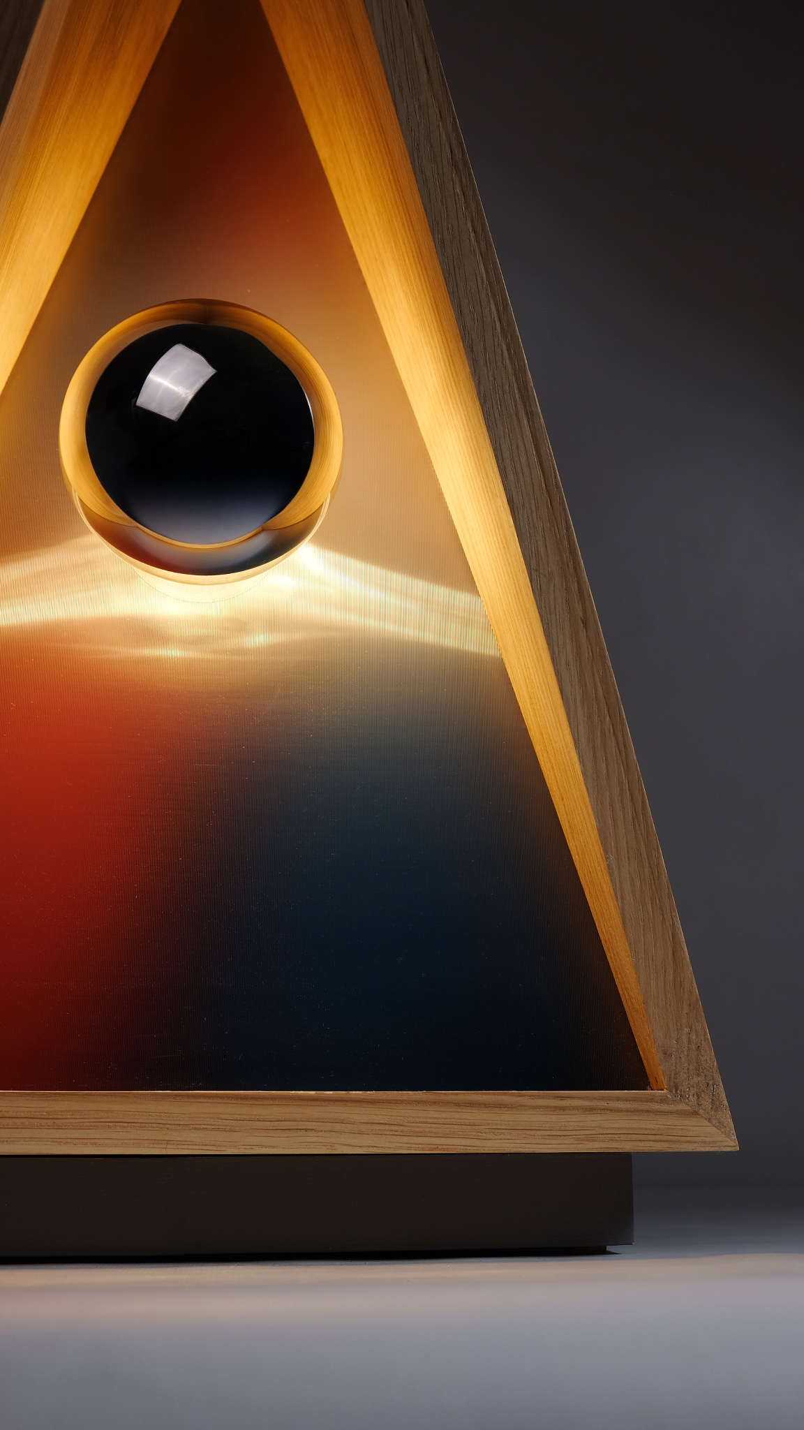 Triangular tabletop lighting fixture with orange and blue tones in the center.