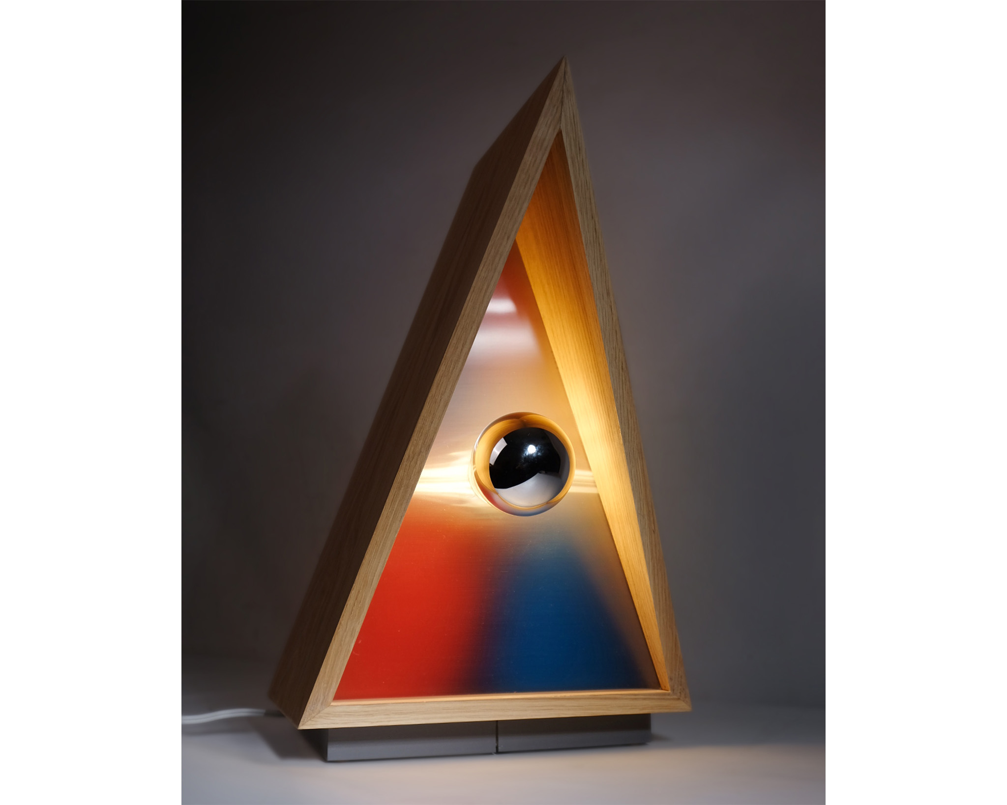 Triangular tabletop lighting fixture with orange and blue tones in the center.