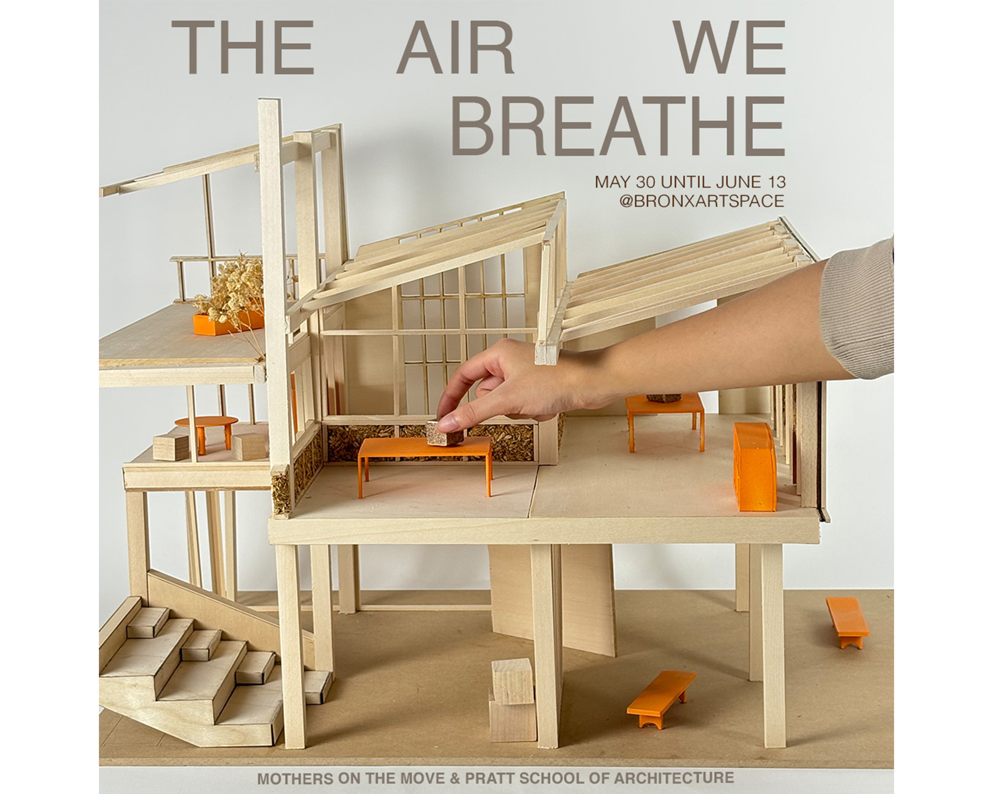 Architectural model of bio-based exhibition space with a hand placing a hemp block on a table.