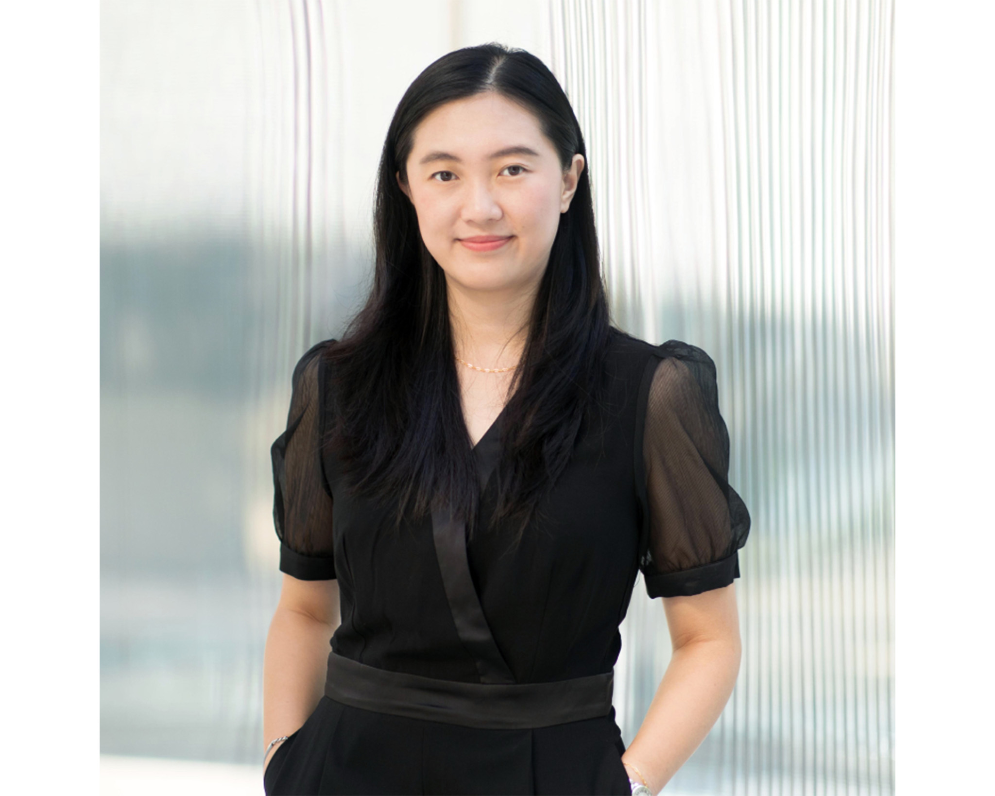 Woman wearing black top and pants with hands in pockets.