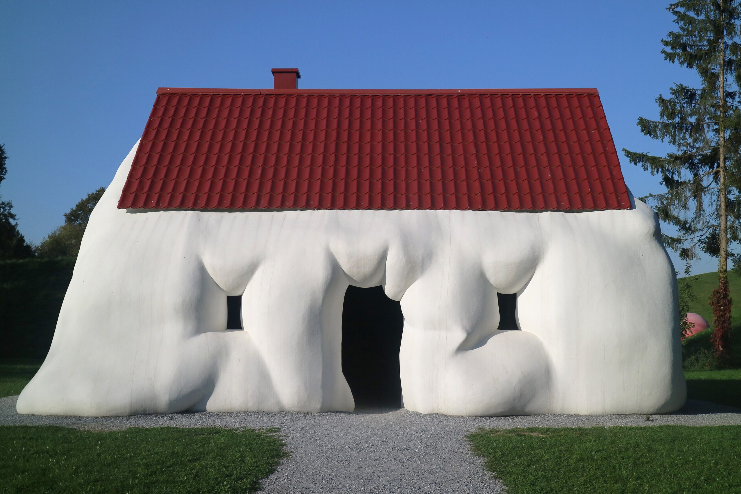 Erwin Wurm's Fat House. It's a house which looks inflated, rounded edges and pinching at the openings occurs. The marshmallow-like volume of the home is capped by a ride tile roof - not inflated.