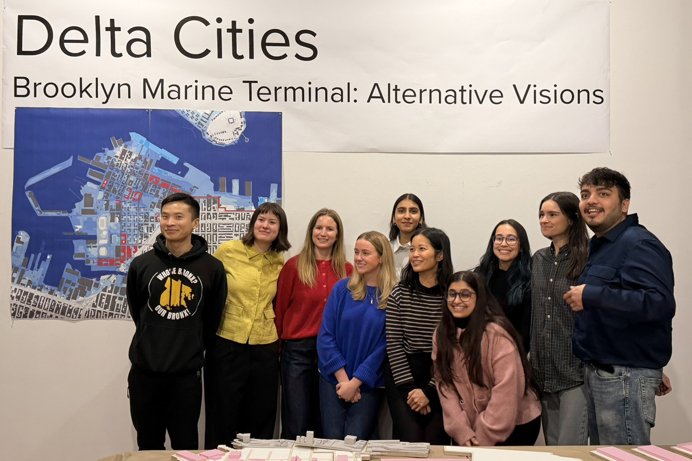 A group of ten students poses in front of an exhibit of research findings.