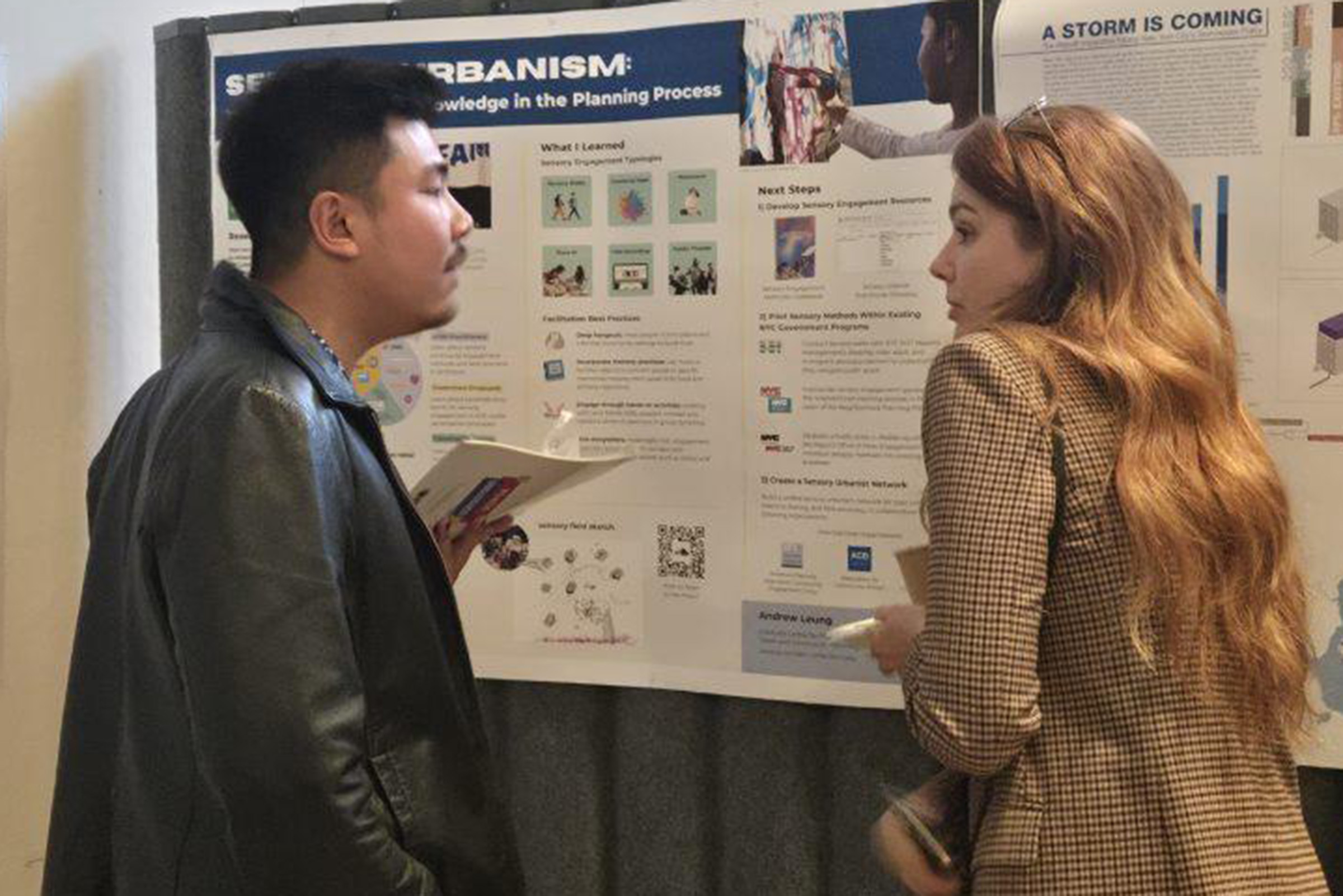 Two students are discussing research outlined in a poster display.
