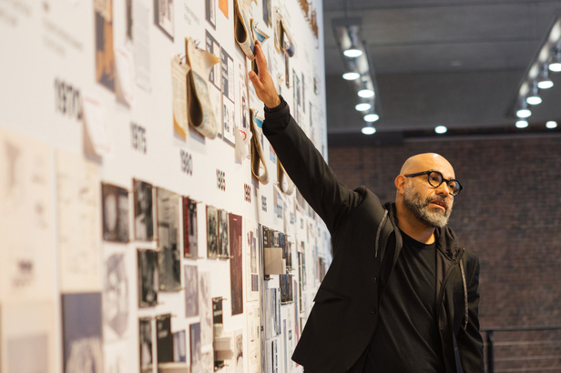 Man raises arm to exhibition wall.