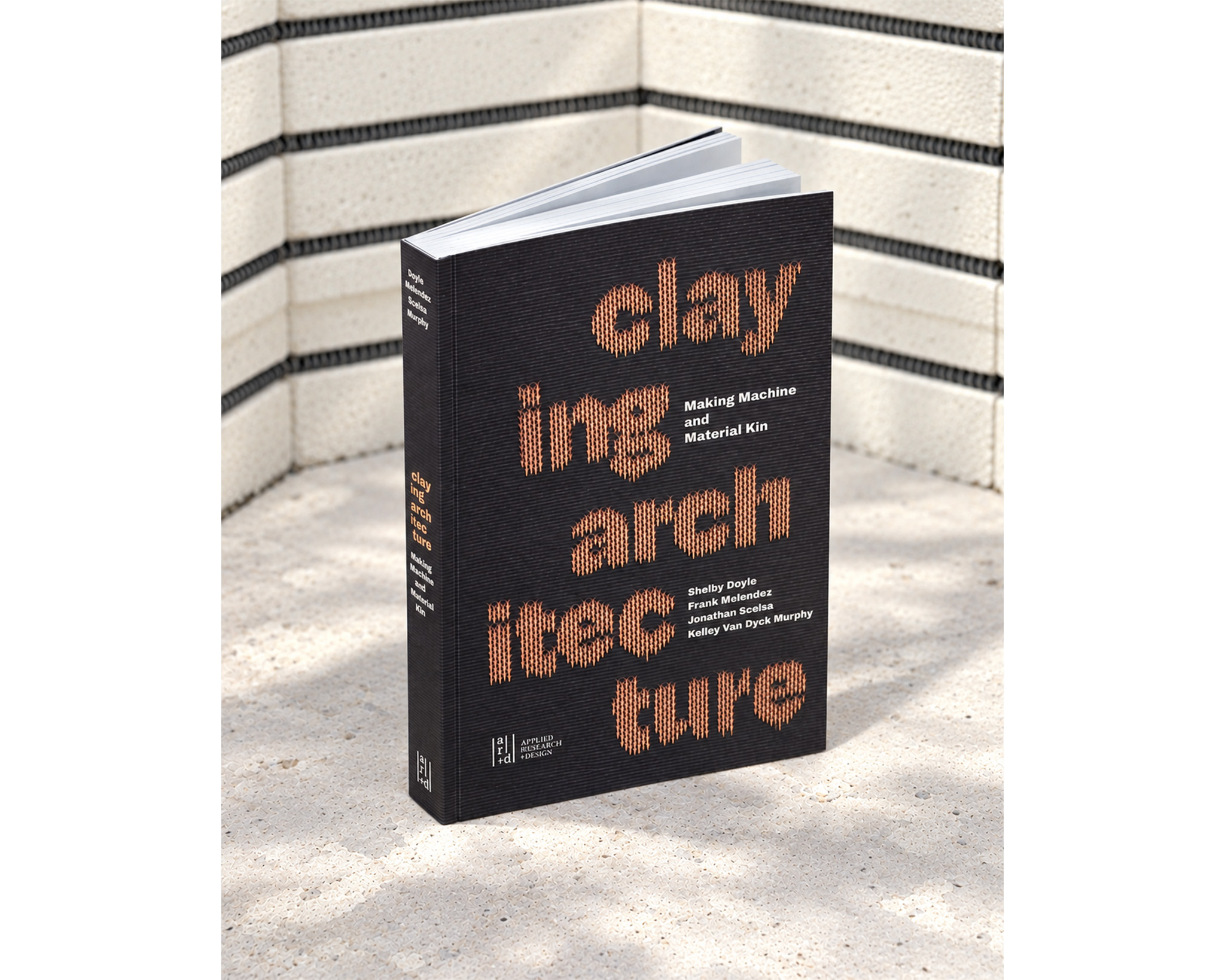The book Claying Architecture standing upright against a white background. The book is black and the title's lettering is orange.