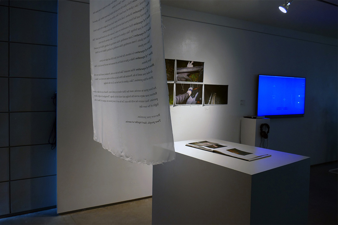 A script in a room with a few black paintings, an island countertop and a tv screen in blue.