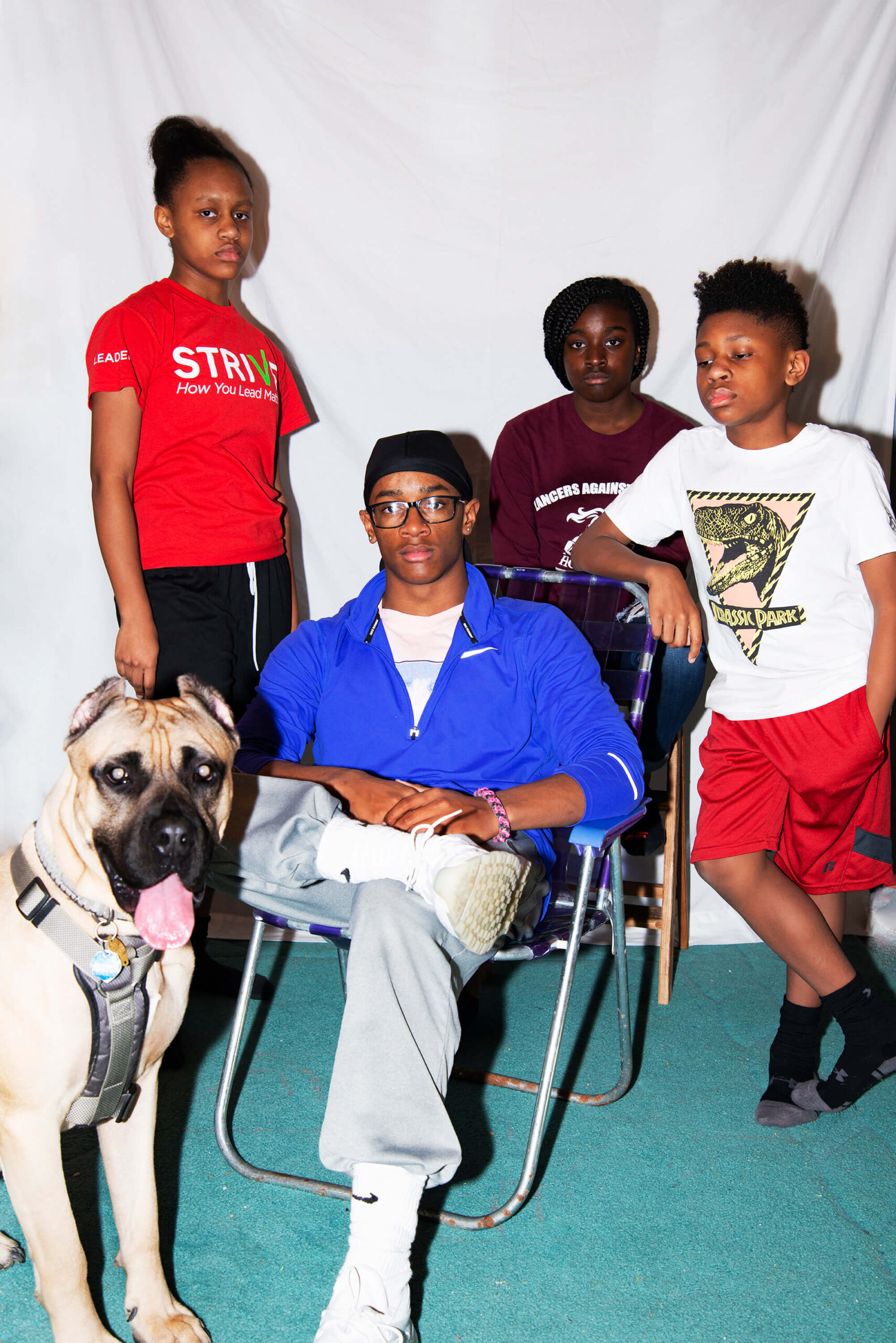 A family and their dog pose for a photograph with solemn facial expressions.