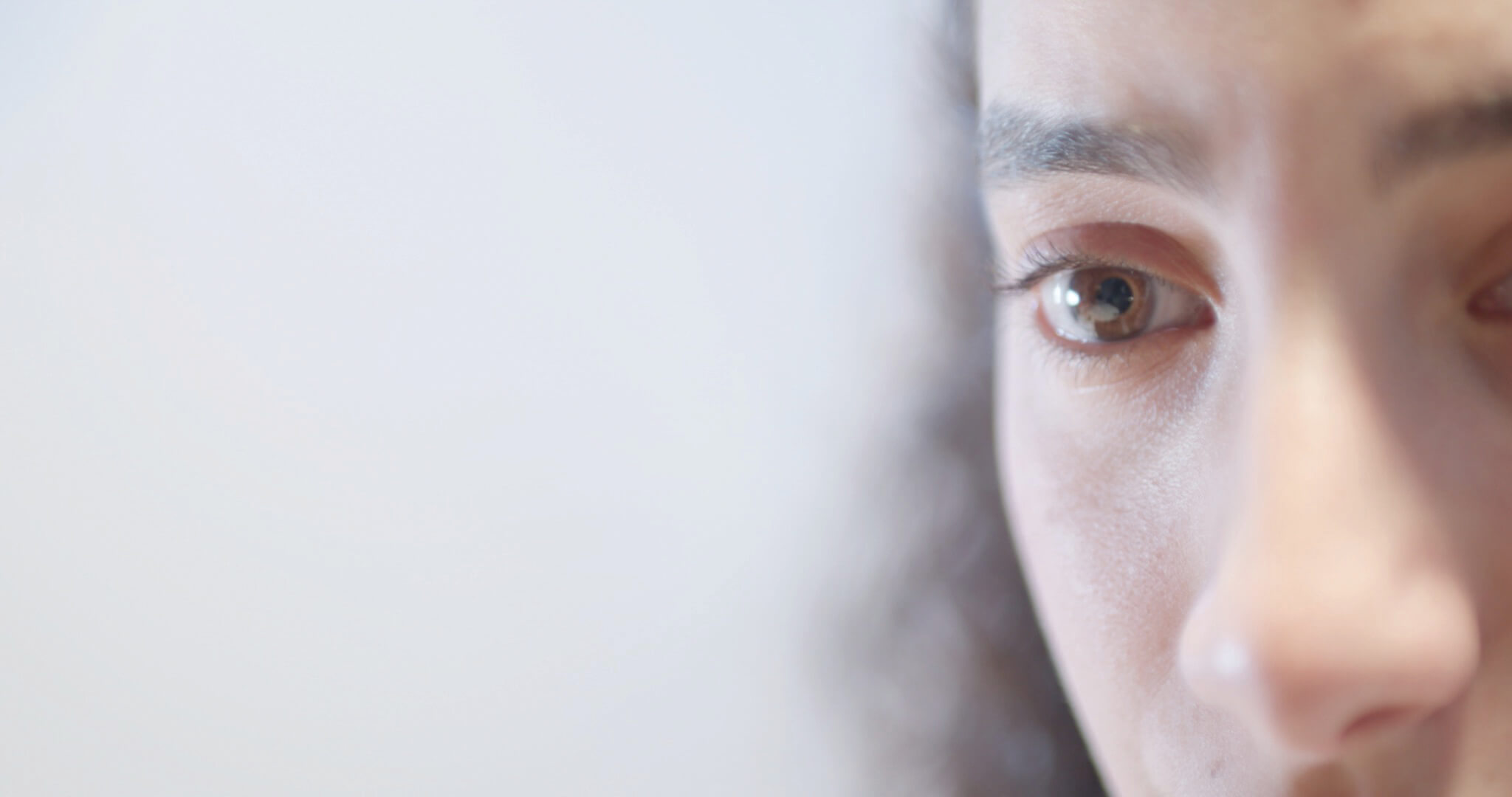 A movie still with a half of person's face in view against a white, smokey background.