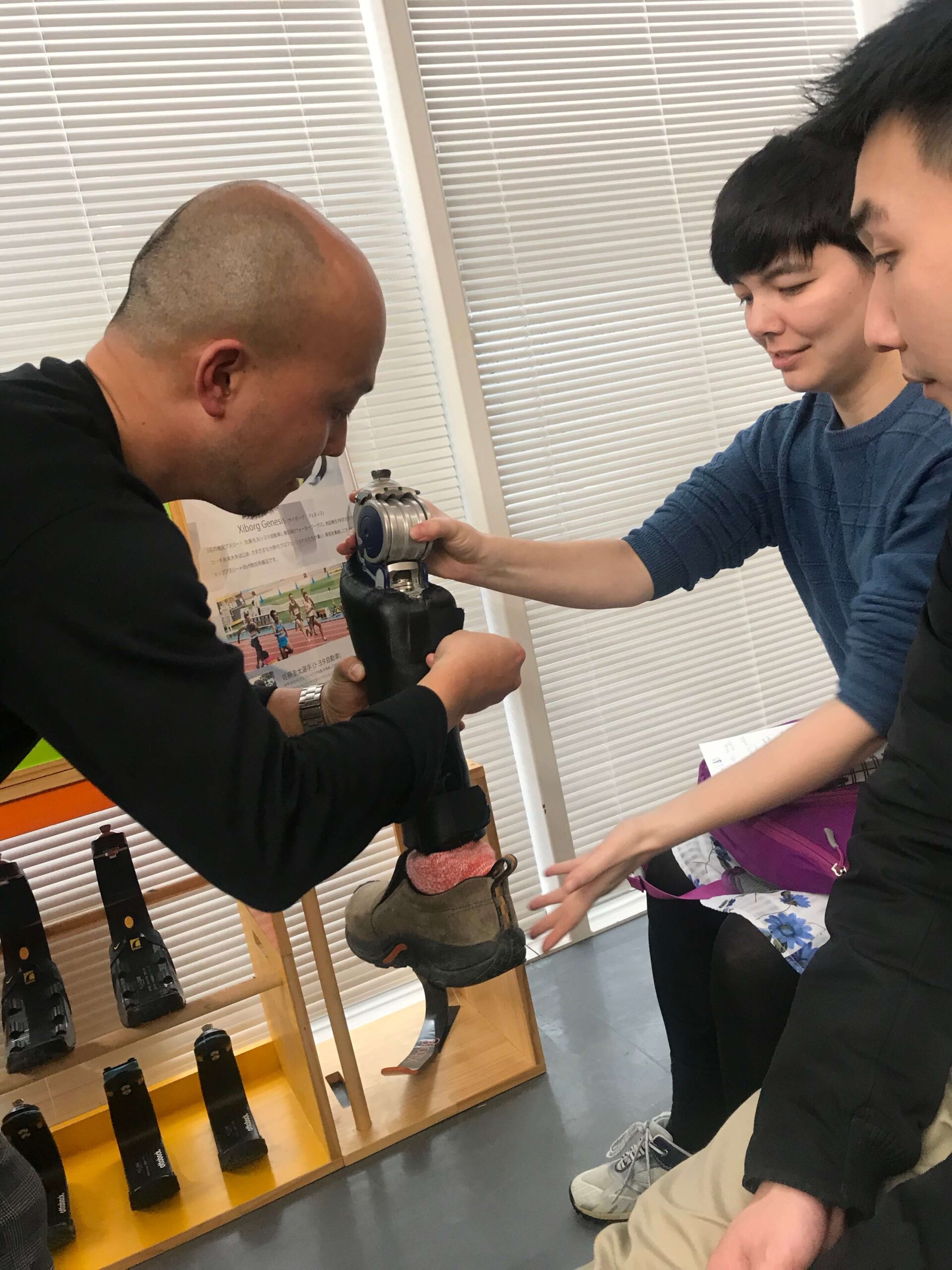 Two students aid a professor in camera demonstration. They are helping him setup the camera on its tripod.