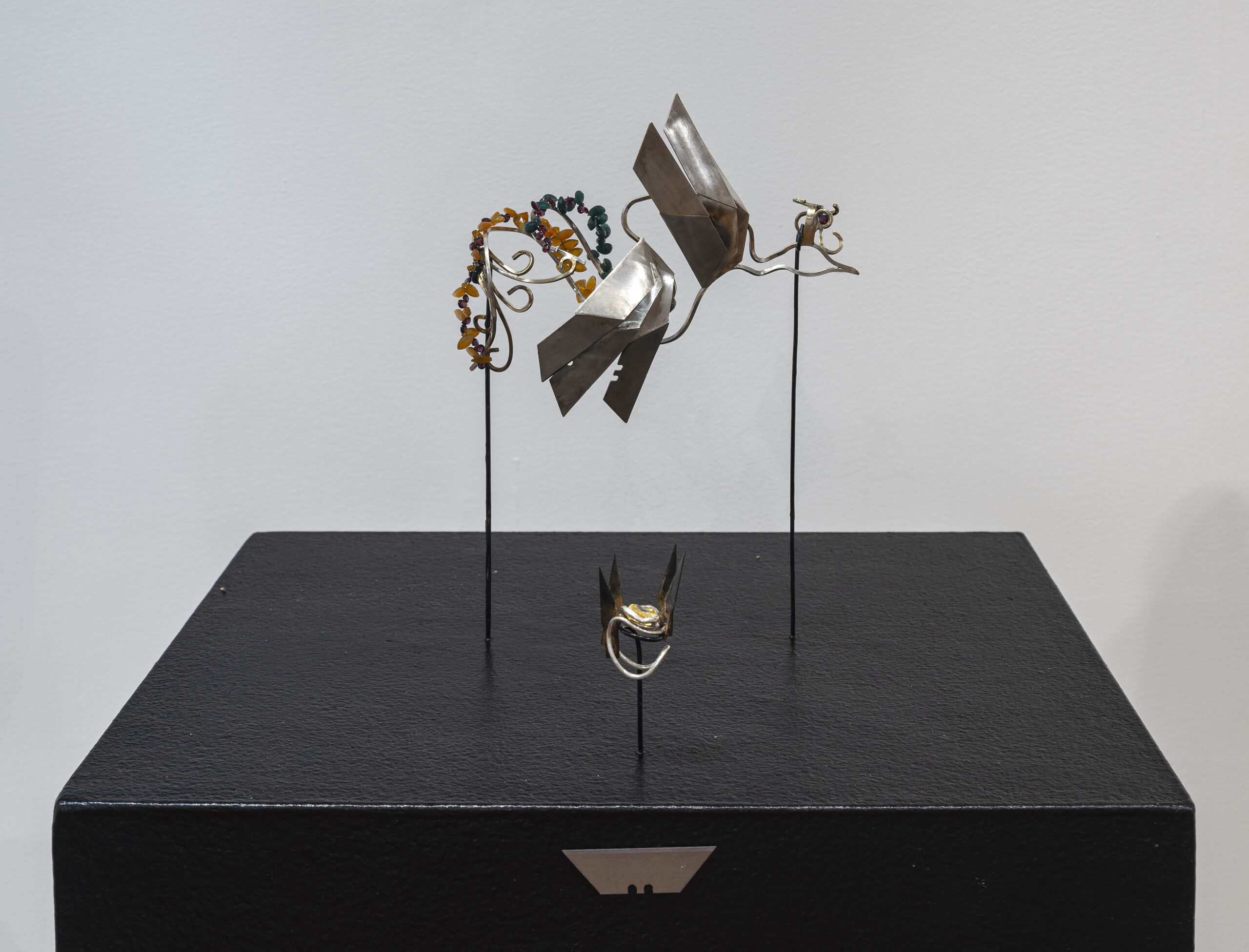 metal bands and objects, on display rods, atop a display platform