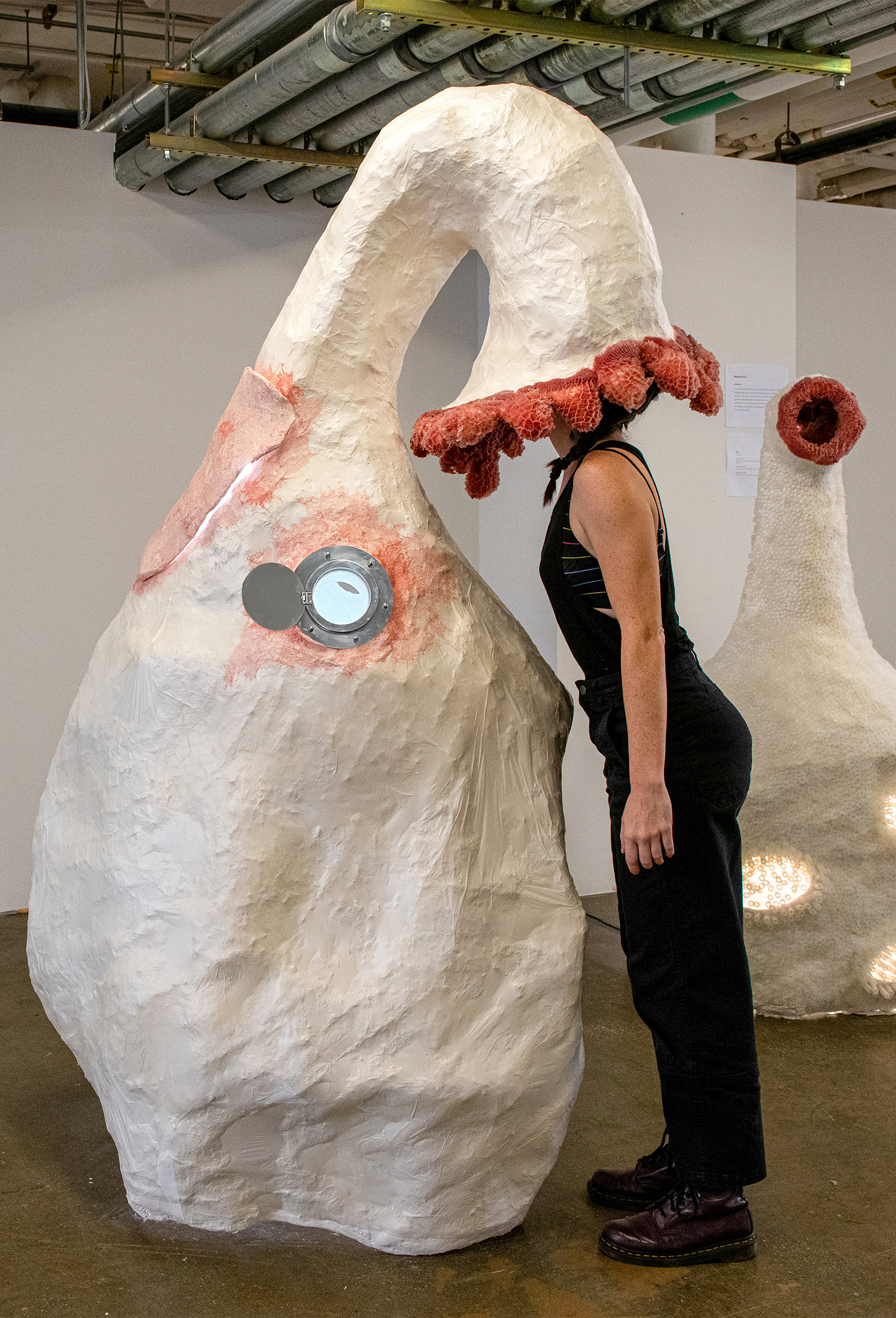 installation, resembles large gourd, woman with her head inside installation, at exhibition