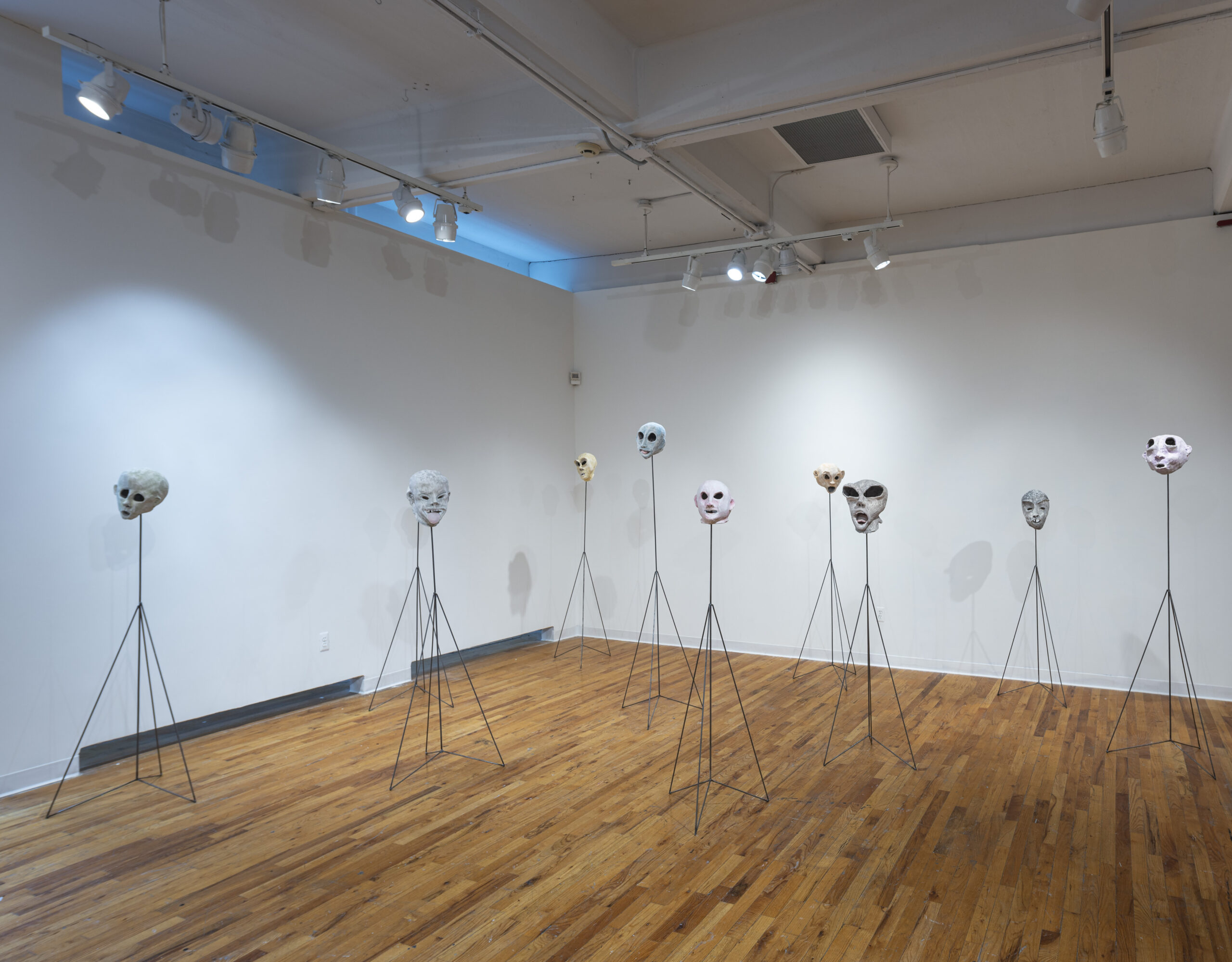 a gallery setting, with 7 face mask sculptures