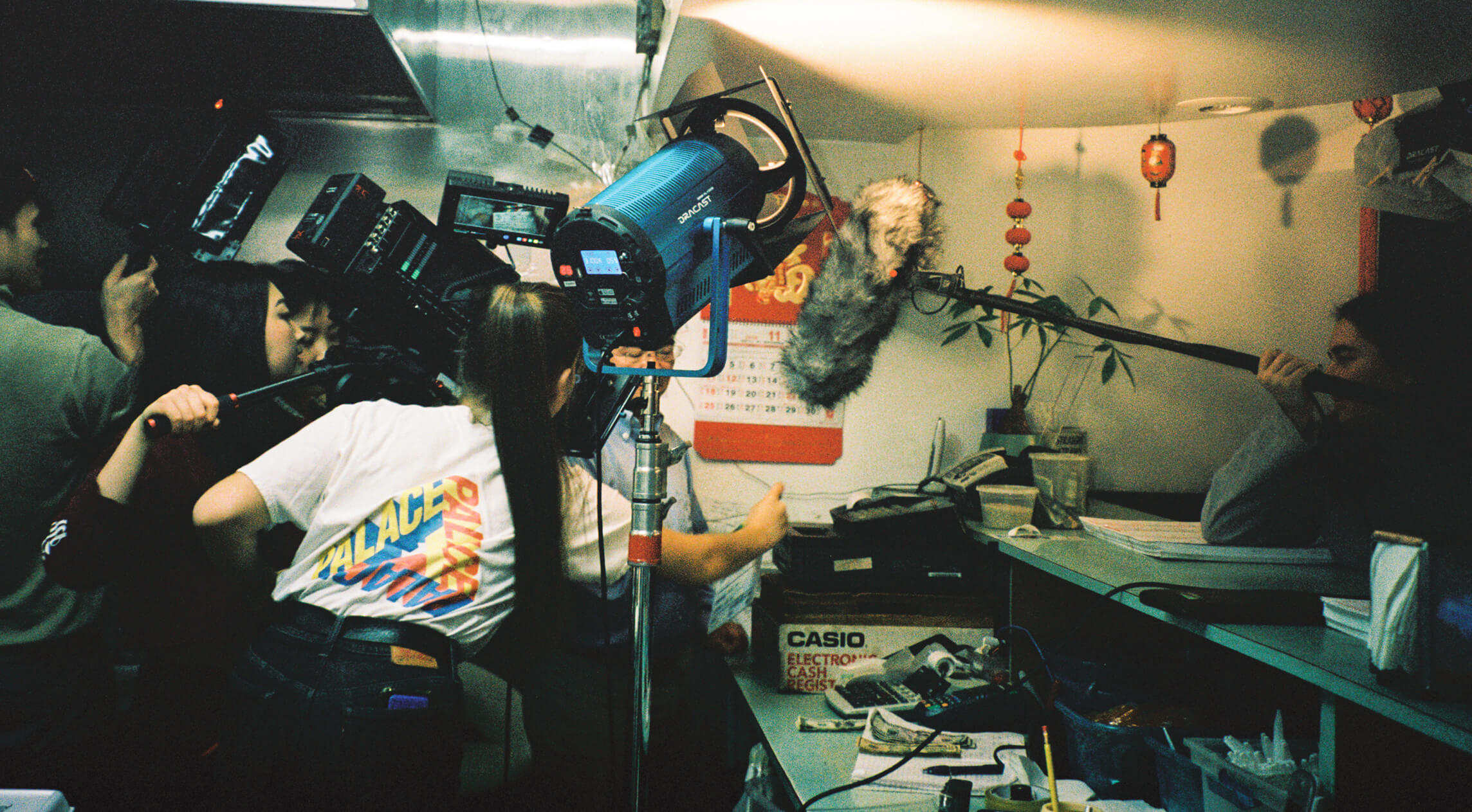 A camera crew works with a variety of equipment in a cramped room.