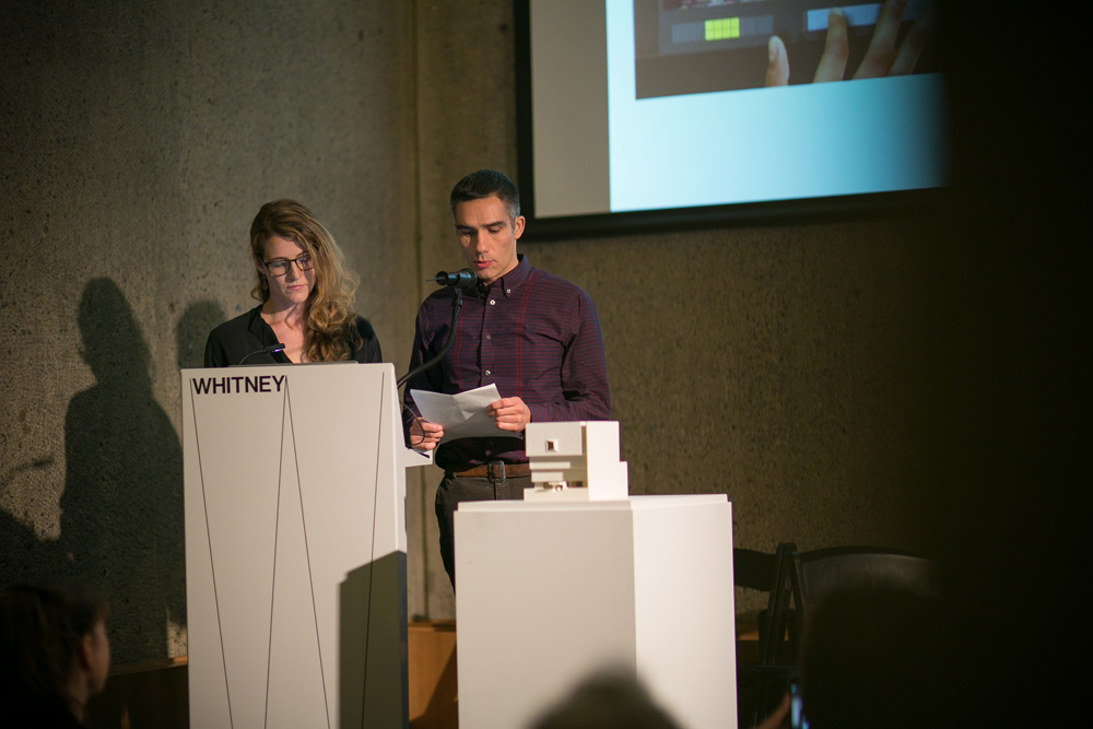 Image of João Enxuto & Erica Love on a stage, presenting.