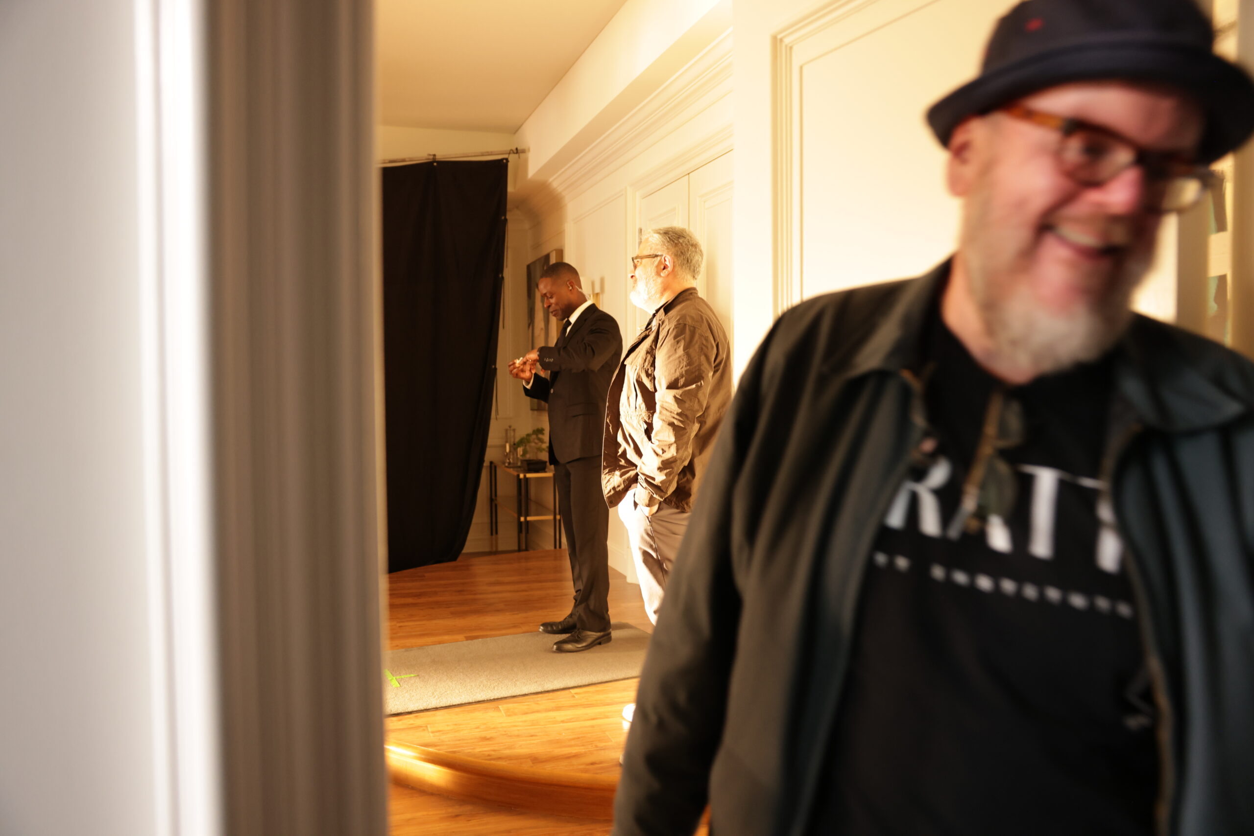 A photograph of a film set with a bearded man in a hat facing the camera.