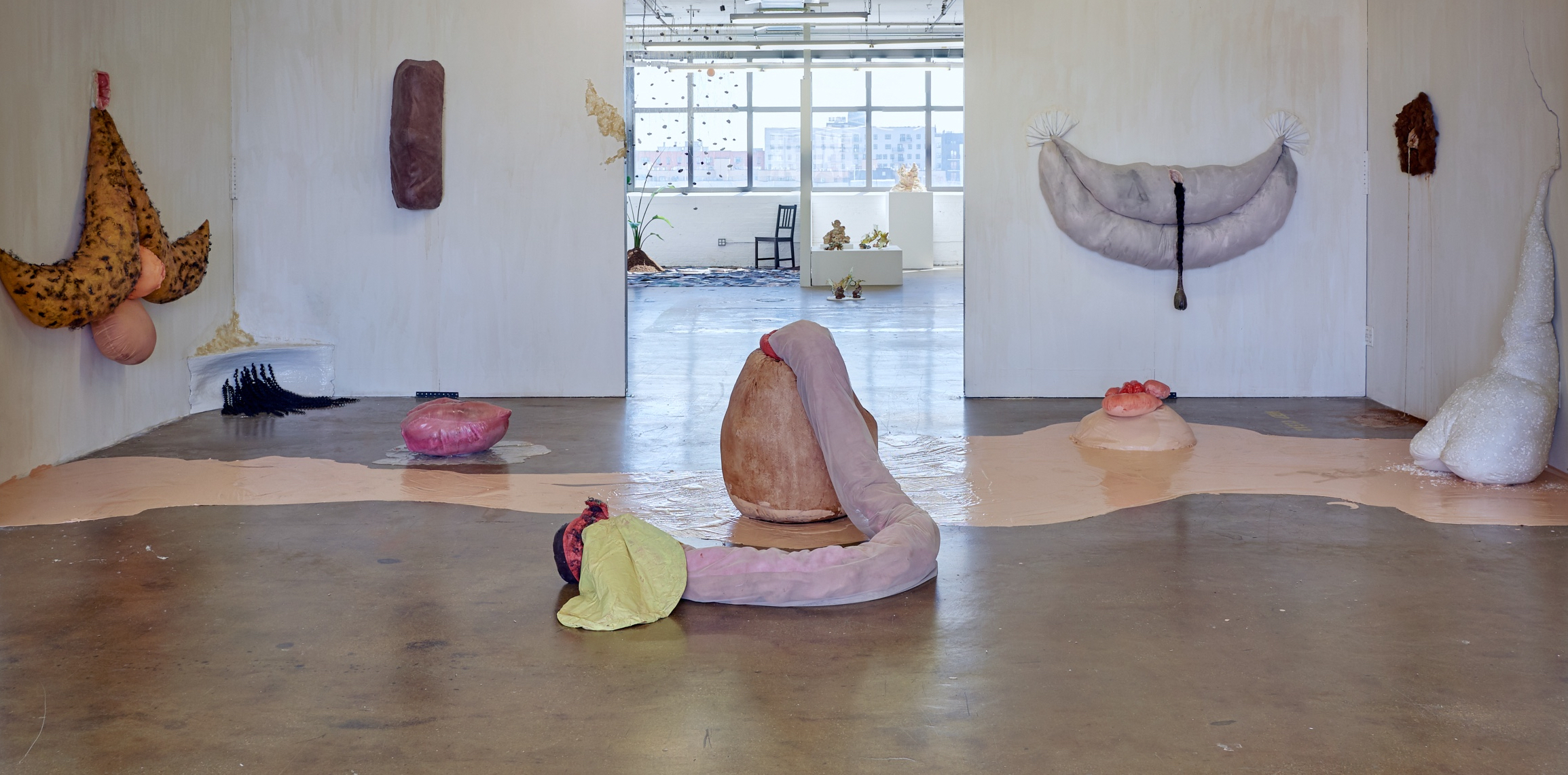 concrete sculpture with fabric coil coming out of the top, with blue circular base, in a room exhibited with other sculptures
