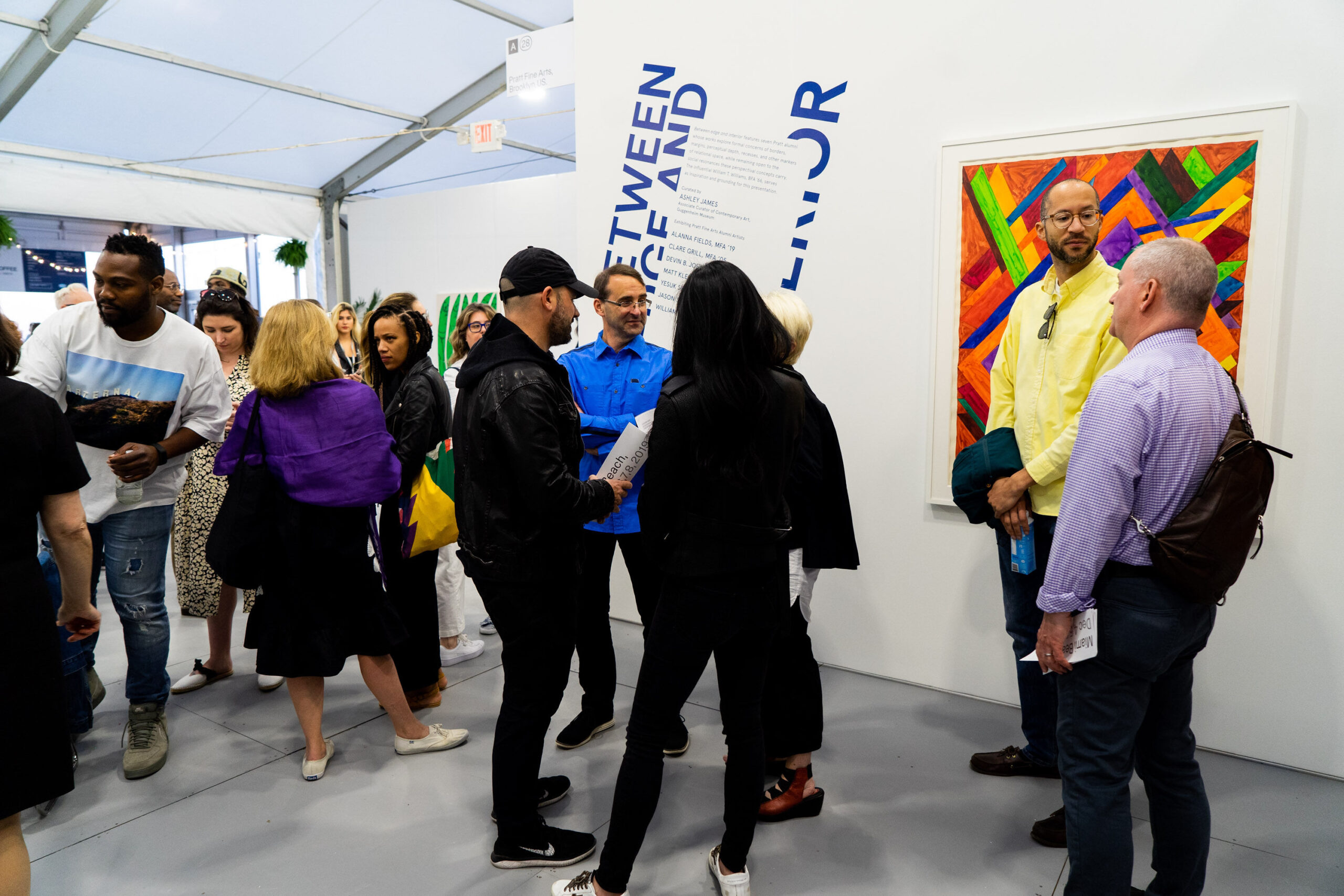 groups of people standing in front of and around artwork in an exhibition