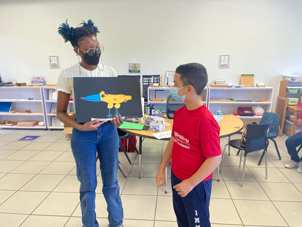 Ife Oluwamuyide (BFA Fine Arts, minor in Teaching Art in NYC, 2022) discussing a collage with an elementary school student, San Juan, Puerto Rico. (keep this photo small)