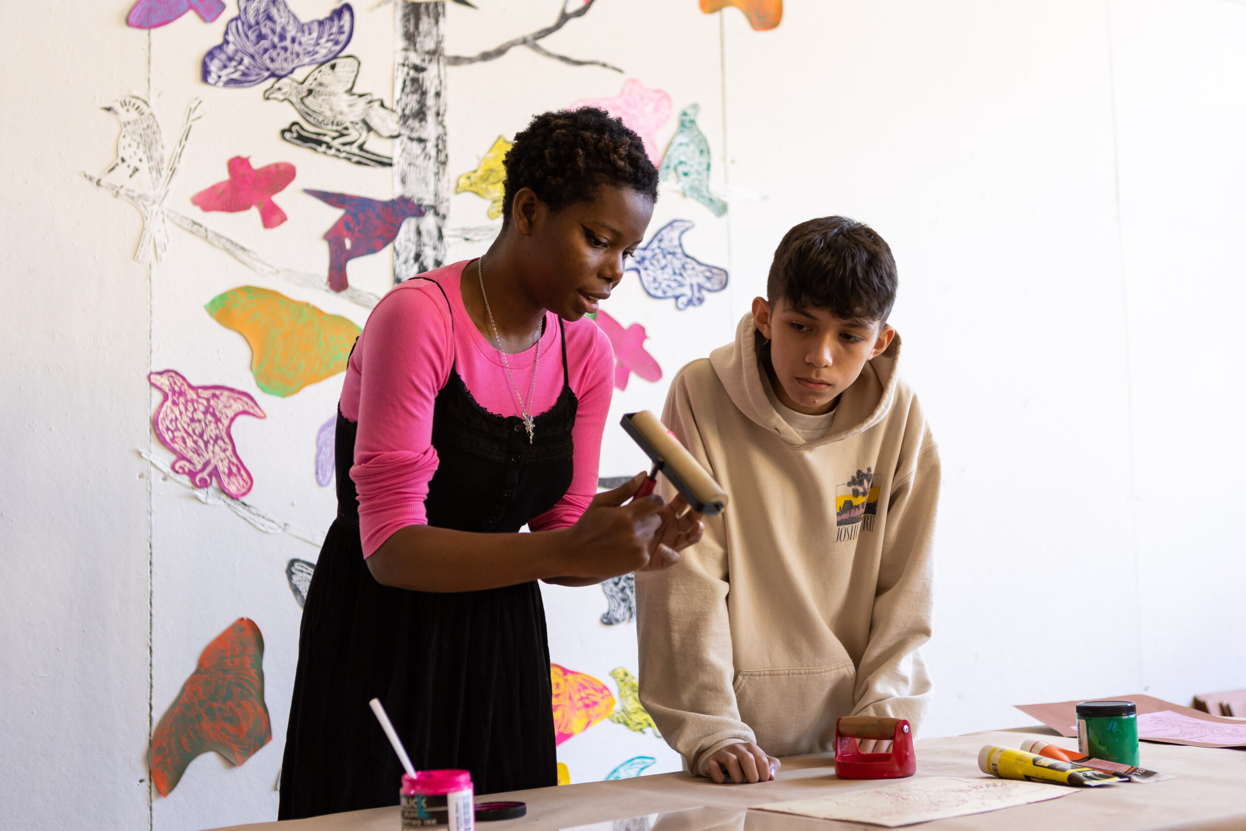 two students in an art studio room, with an abstract painting behind them