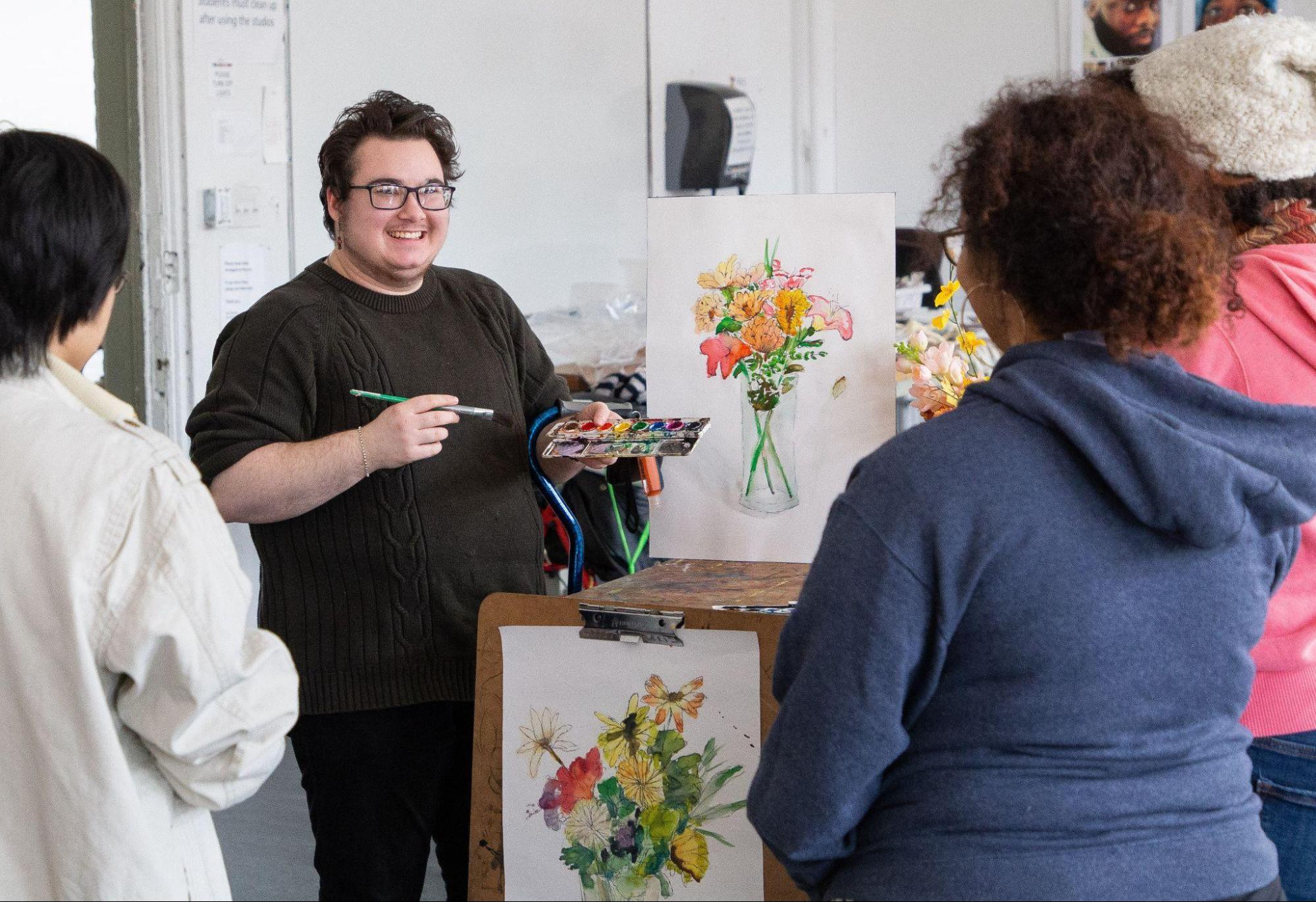 professor speaking with students, in a art studio, with paint brush in hand