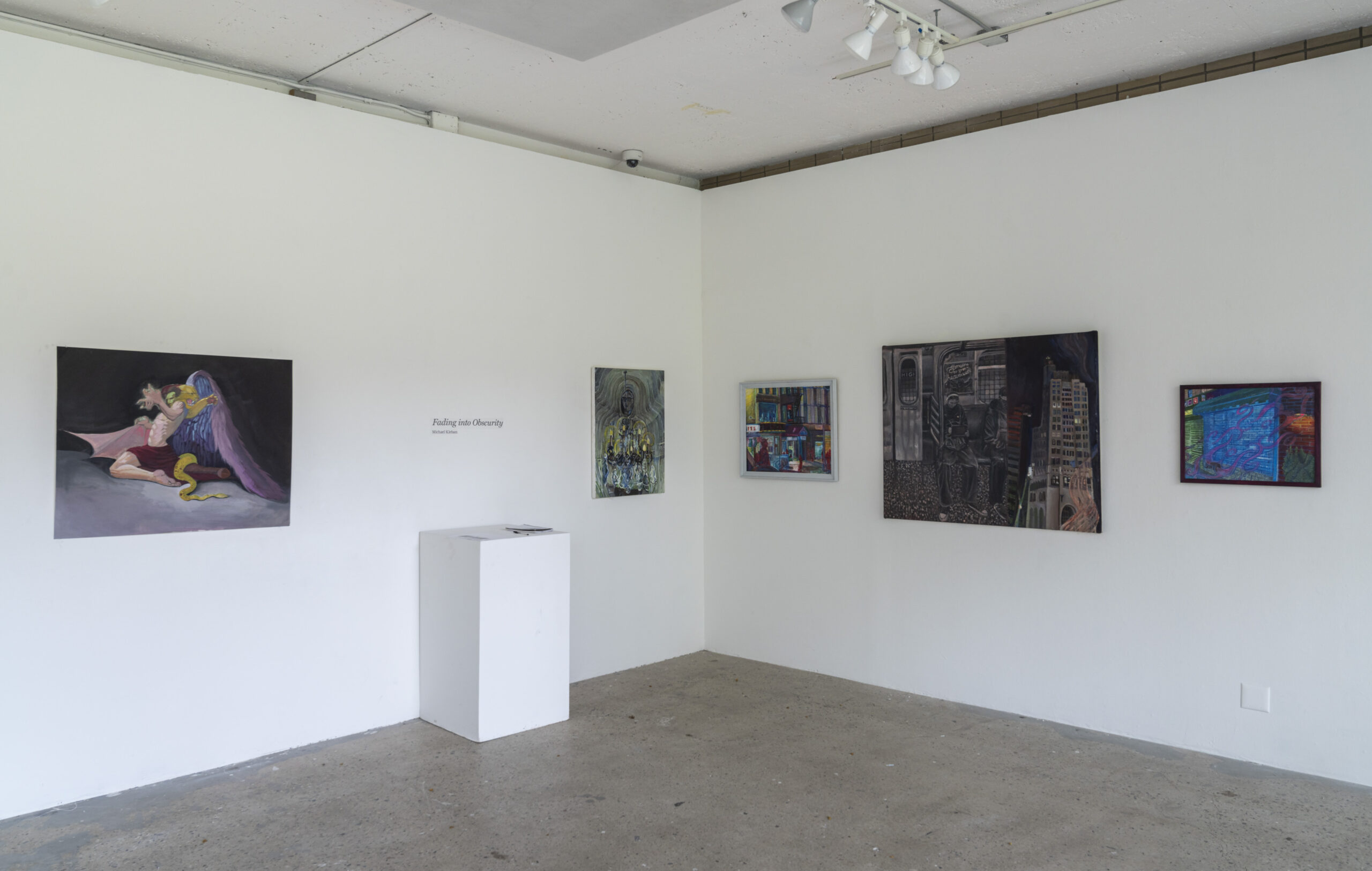 A contemporary gallery space with a long white wall displaying a series of small to medium-sized paintings. The artworks range from intricate black-and-white illustrations to expressive, colorful compositions. On the right side, a prominent painting of a cloaked figure interacting with a serpent is highlighted. The gallery floor is made of concrete, and the space is illuminated by overhead spotlights.