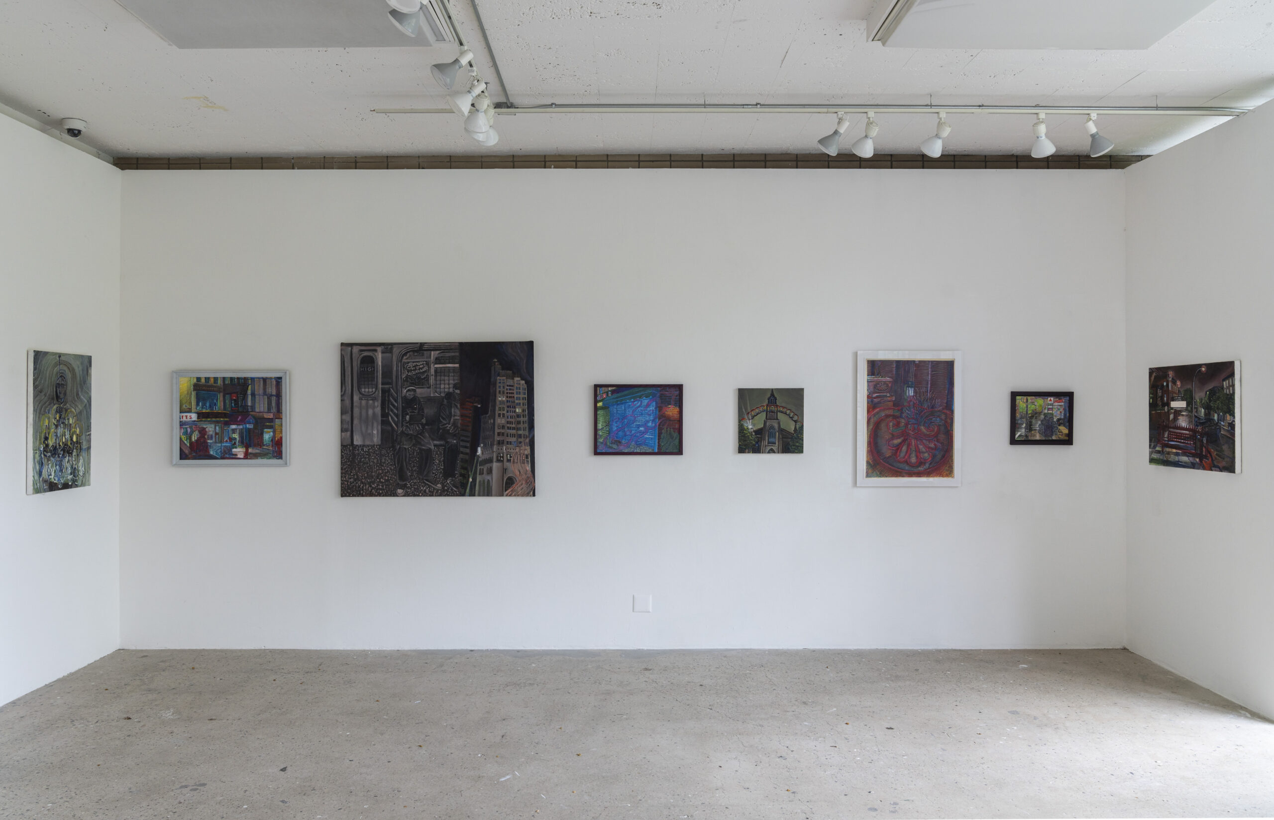 A corner of a gallery featuring a series of paintings with urban themes. The leftmost artwork shows a subway scene with two figures sitting in a train, followed by smaller colorful cityscape-inspired paintings. The right side of the image includes a window showing greenery outside. The gallery has a minimalist design with a white wall and a polished concrete floor.