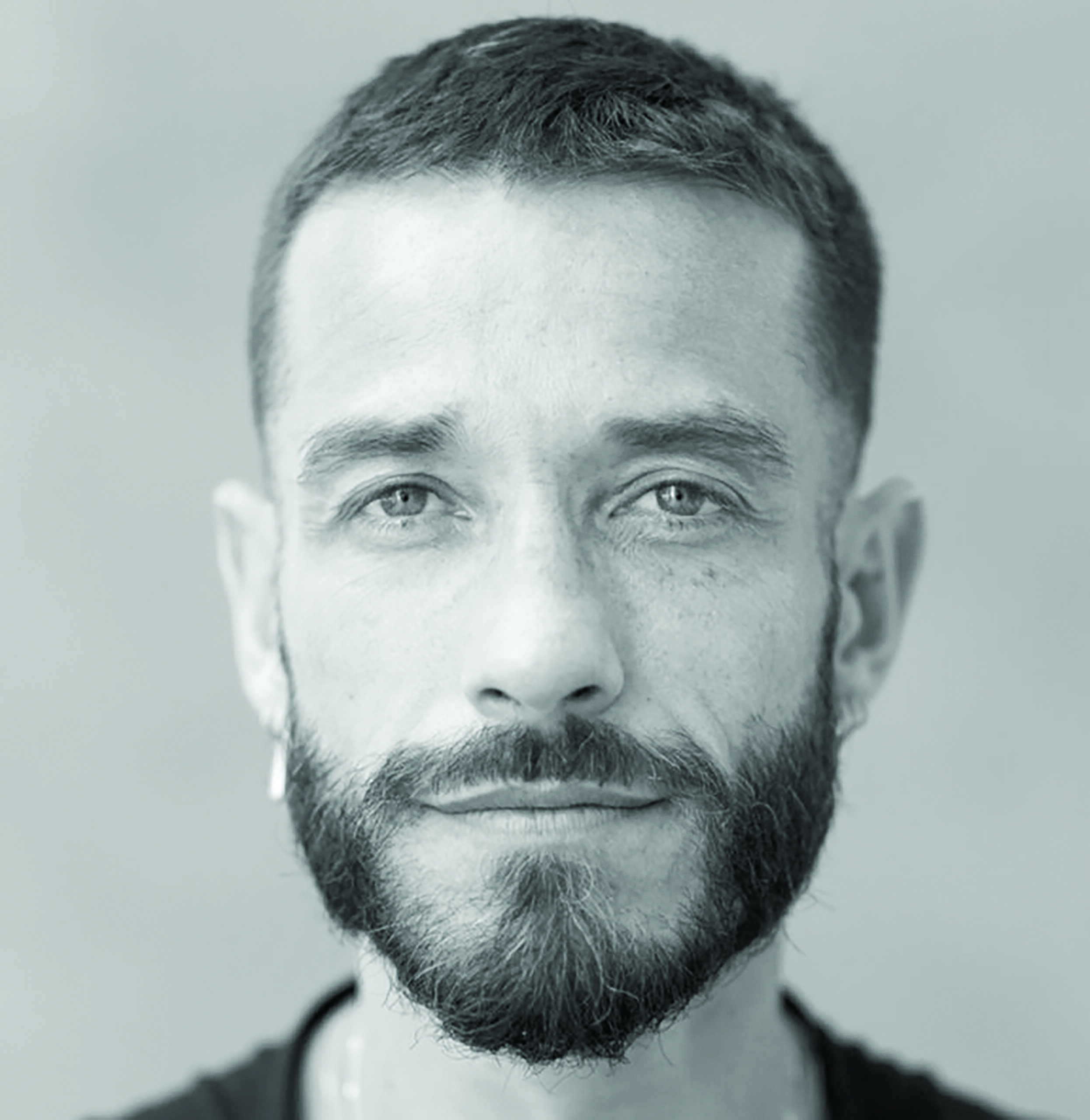 Black and grey headshot of Carlos Motta, center of frame and looking straight ahead at the camera.
