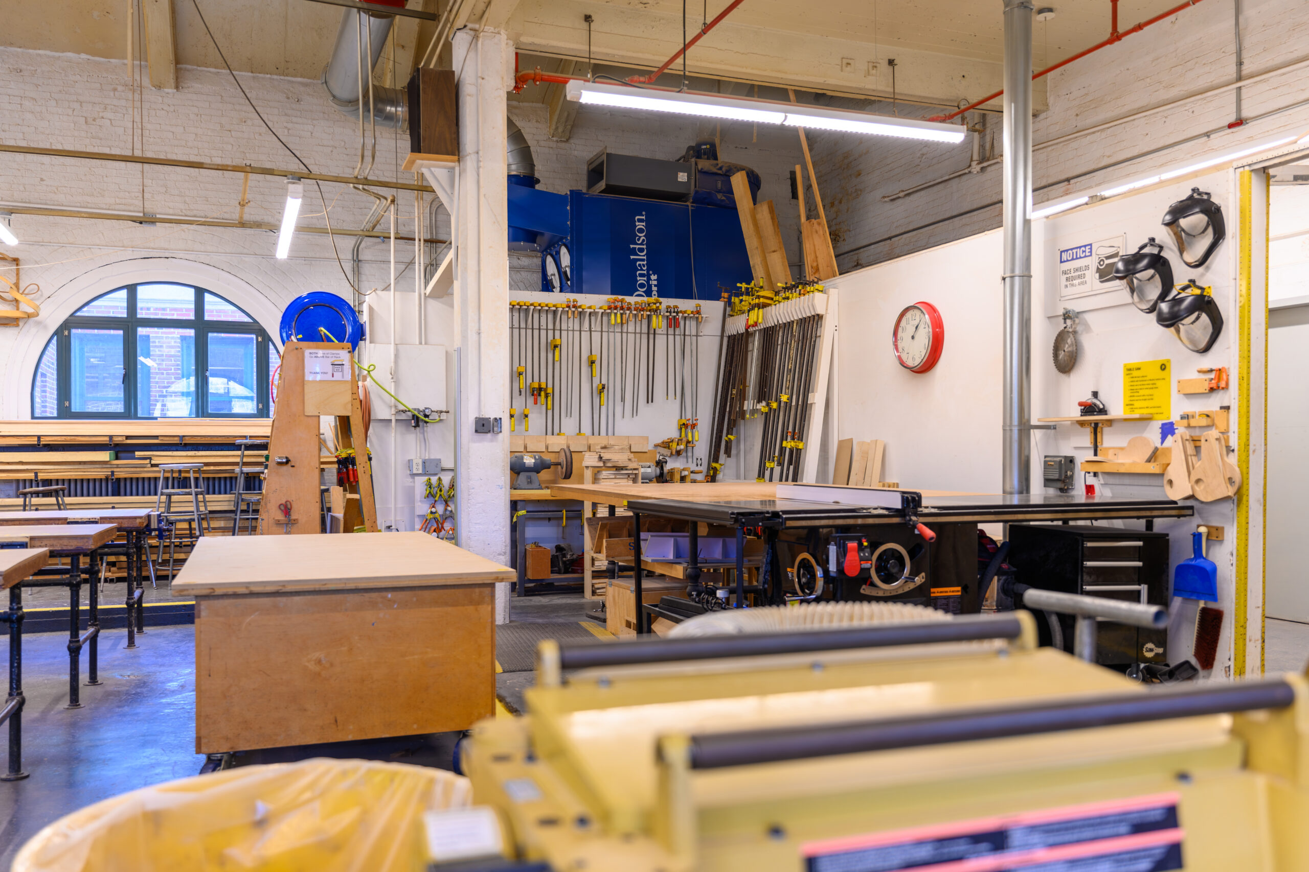 Equipment in the Fine Arts woodshop. Clamps and safety equipment hand on the walls.
