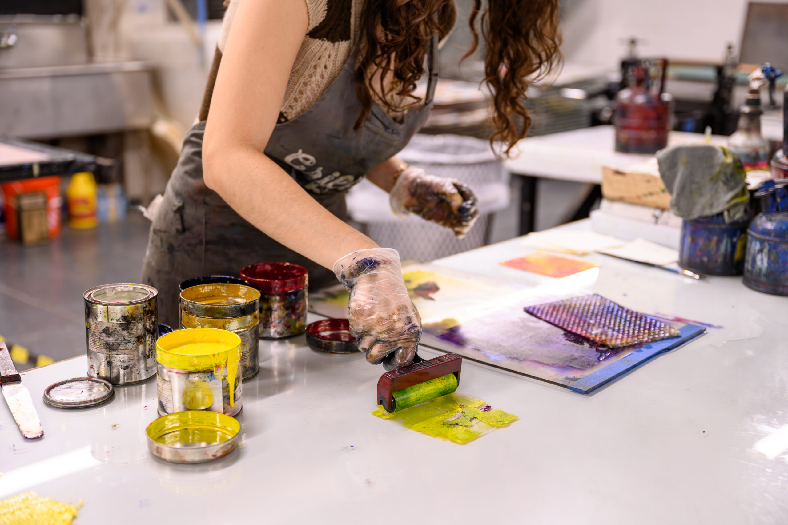 A student rolls out mixed colored inks with a brayer on glass.