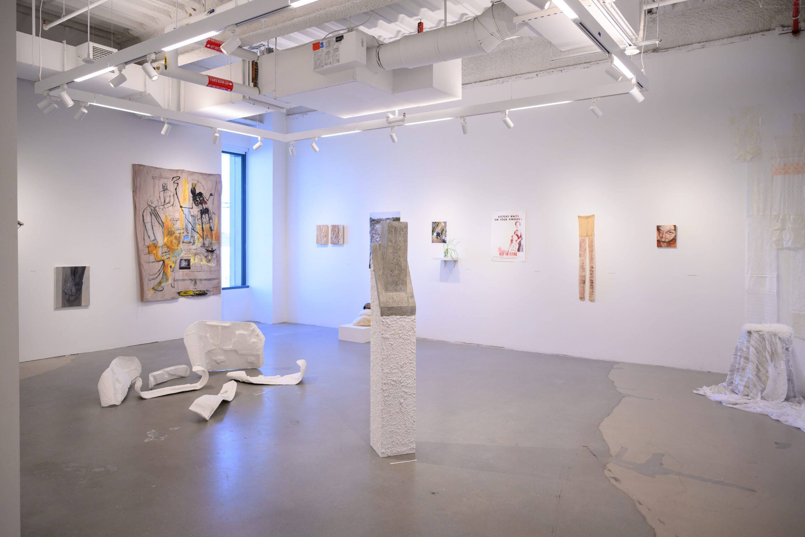 A brightly lit gallery with white and light-neutral artworks on the wall and sculptures on the floor and on pedestals.