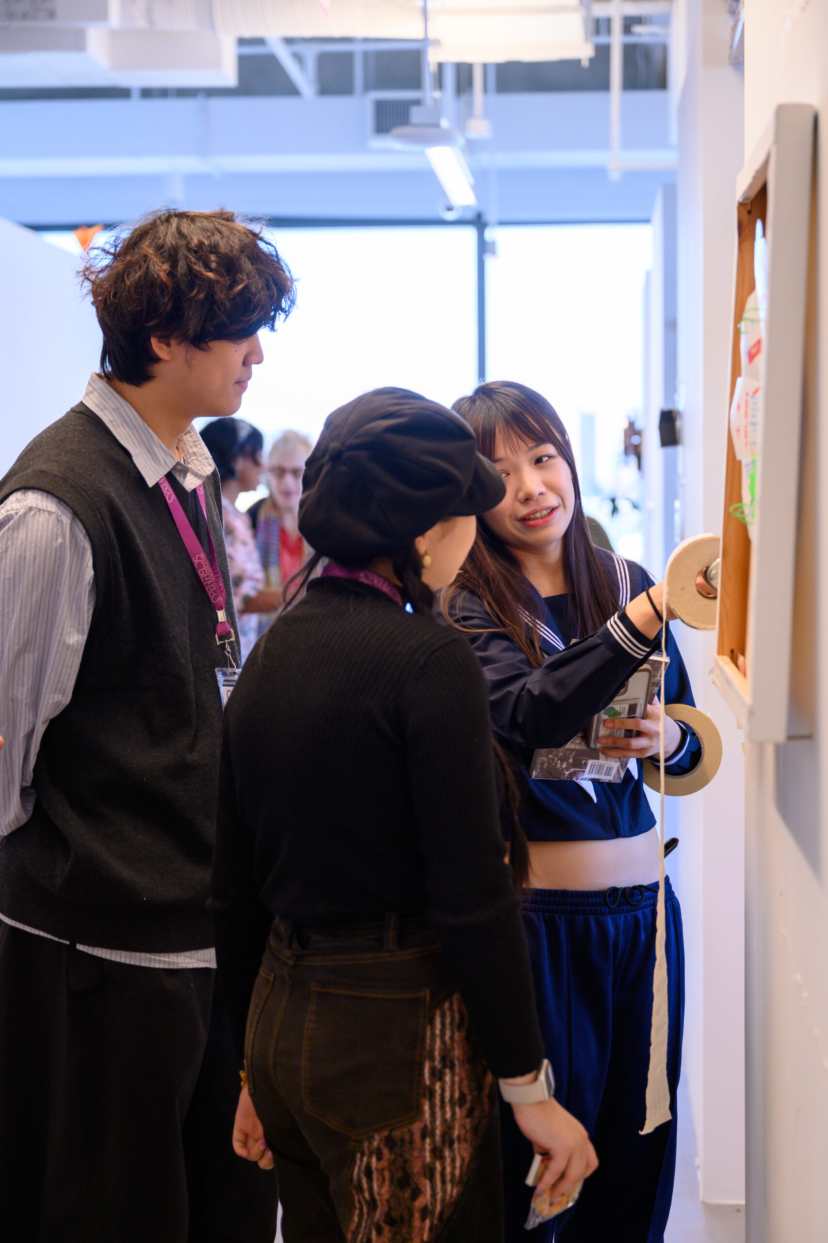 An artist explains their work to two visitors.