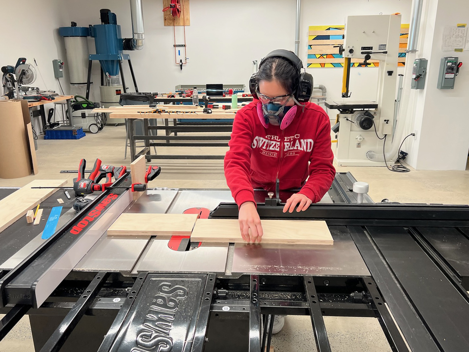 A student cuts a piece of wood in the Dock 72 Fine Arts wood shop.