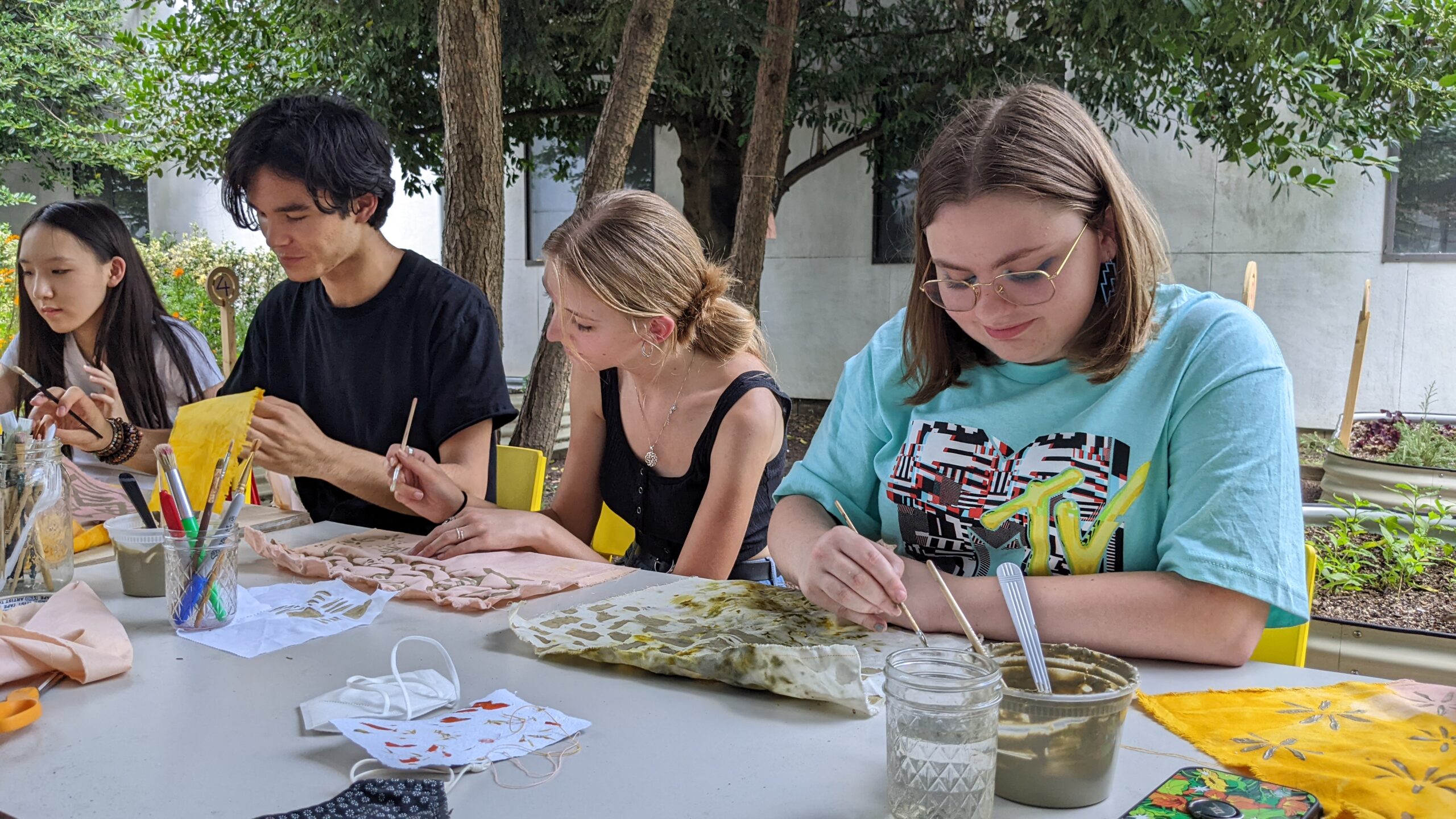 students, seated at a table outside, on campus