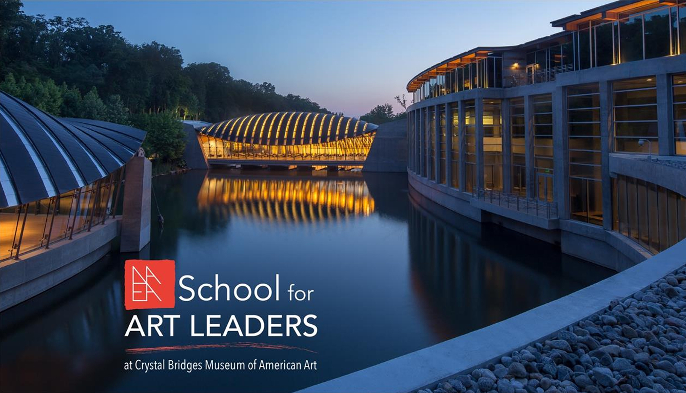 Evening view of the Crystal Bridges Museum of American Art in Bentonville, Arkansas, showing its distinctive curved, glass-and-wood structures reflected in a still body of water. Warm interior lighting contrasts with the cool blue tones of dusk. Text overlay reads: “School for ART LEADERS at Crystal Bridges Museum of American Art” with the NAEA (National Art Education Association) logo in red.