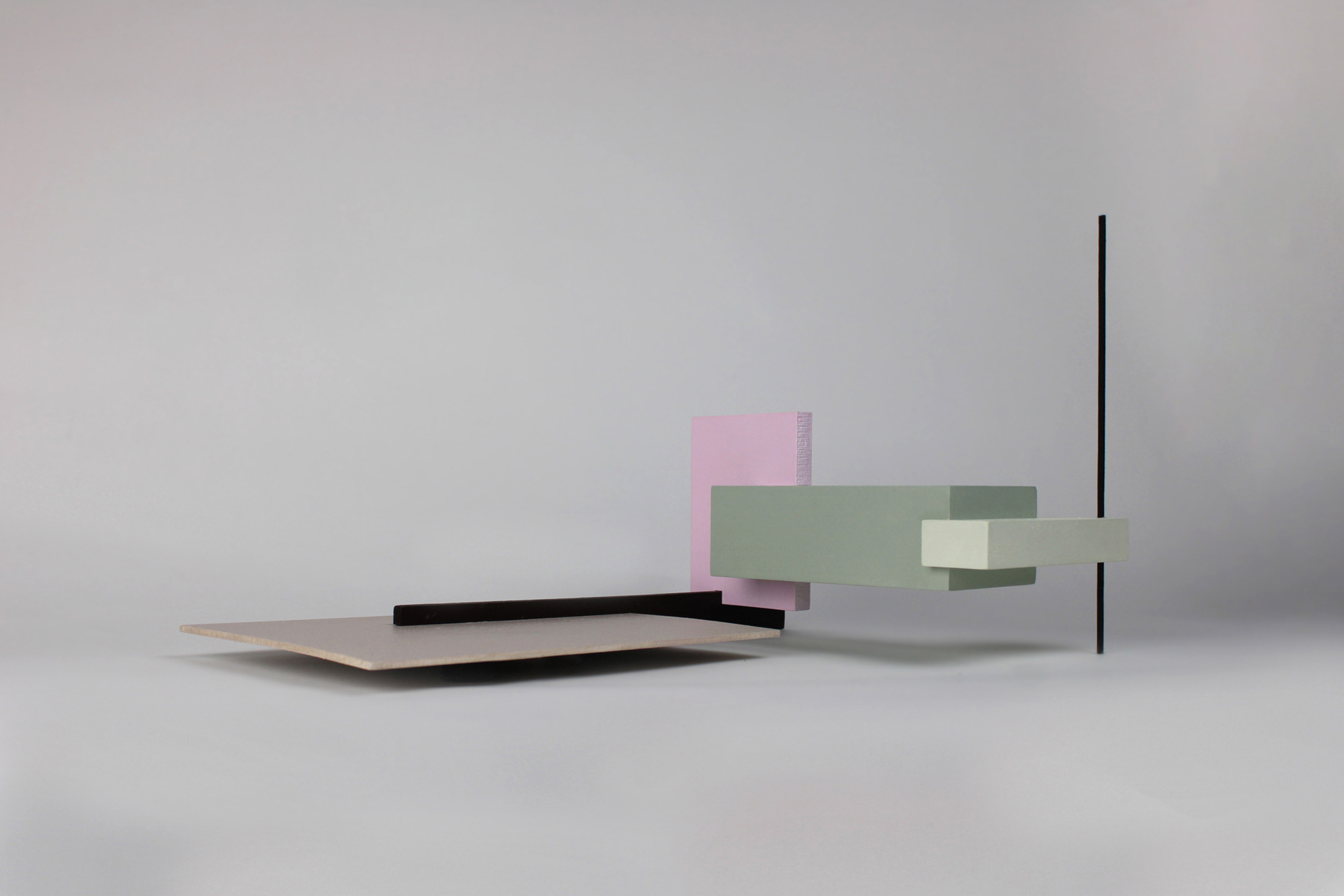 a color photograph of a studio exercise featuring six intersecting rectilinear forms in beige, black, pink, green, and yellow